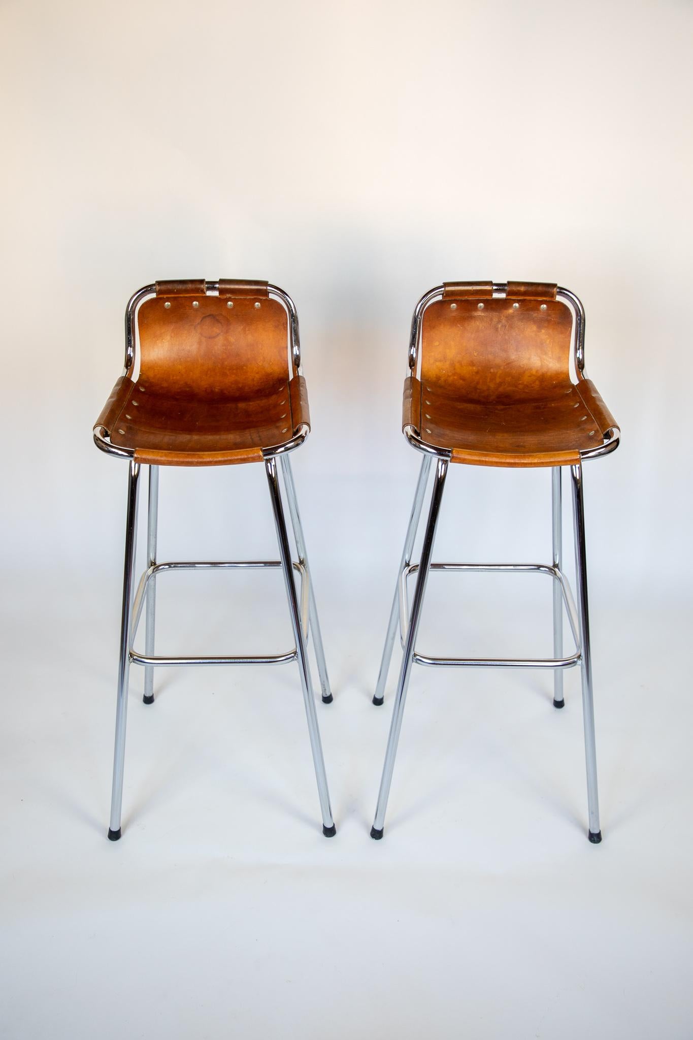 French mid-century saddle leather, brown, chrome bar stools, Perriand, 1960s

Stunning set of 2 French Mid-Century Modern bar stools designed by the famous Designer Charlotte Perriand for the ski resort „Les Arcs“ in France 1960. The stools have
