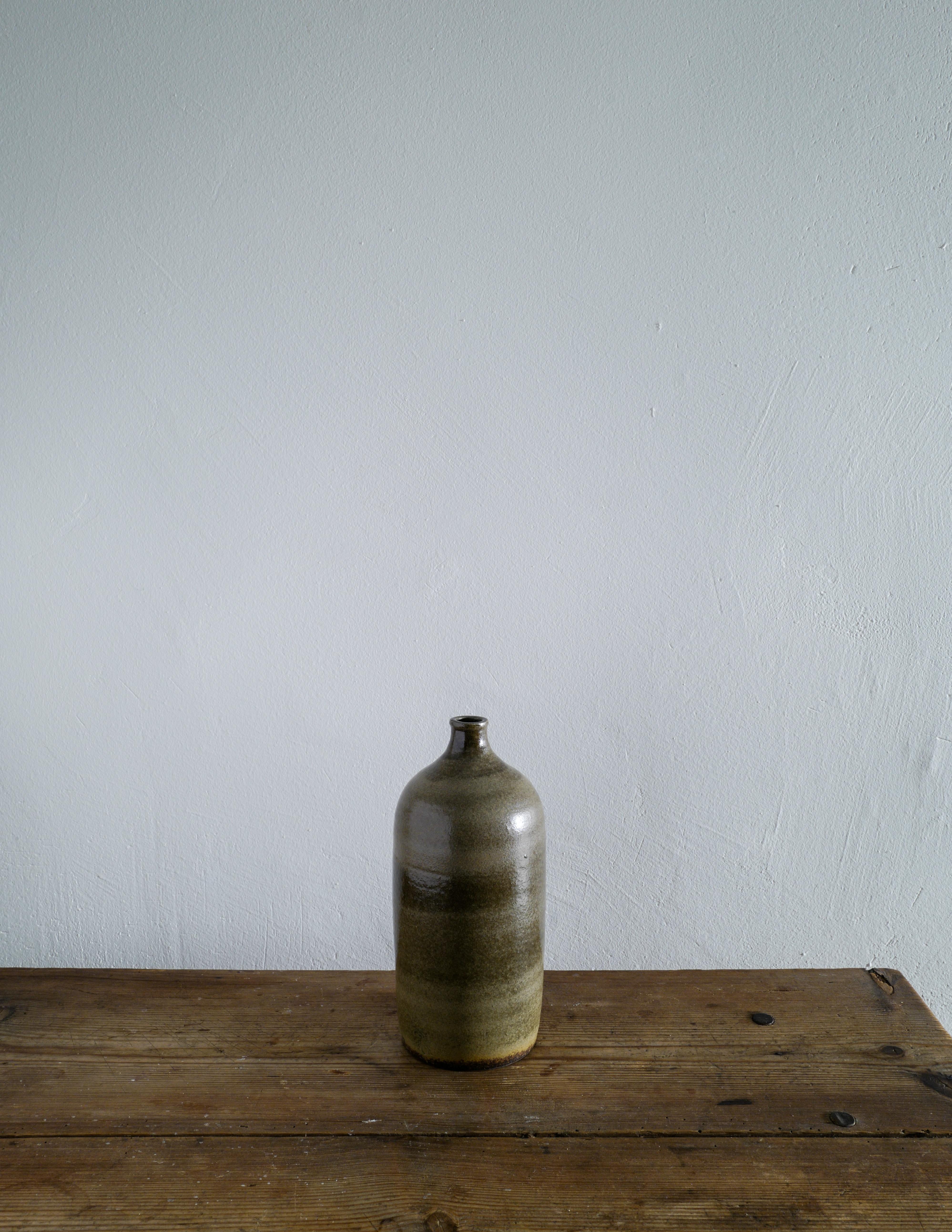 Rare ceramic bottle or vase in green glazed sandstone produced by unknown French designer in the 1950s. In good vintage condition with minimal signs from age and use. 

Dimensions: Height: 25 cm Diameter: 12 cm.