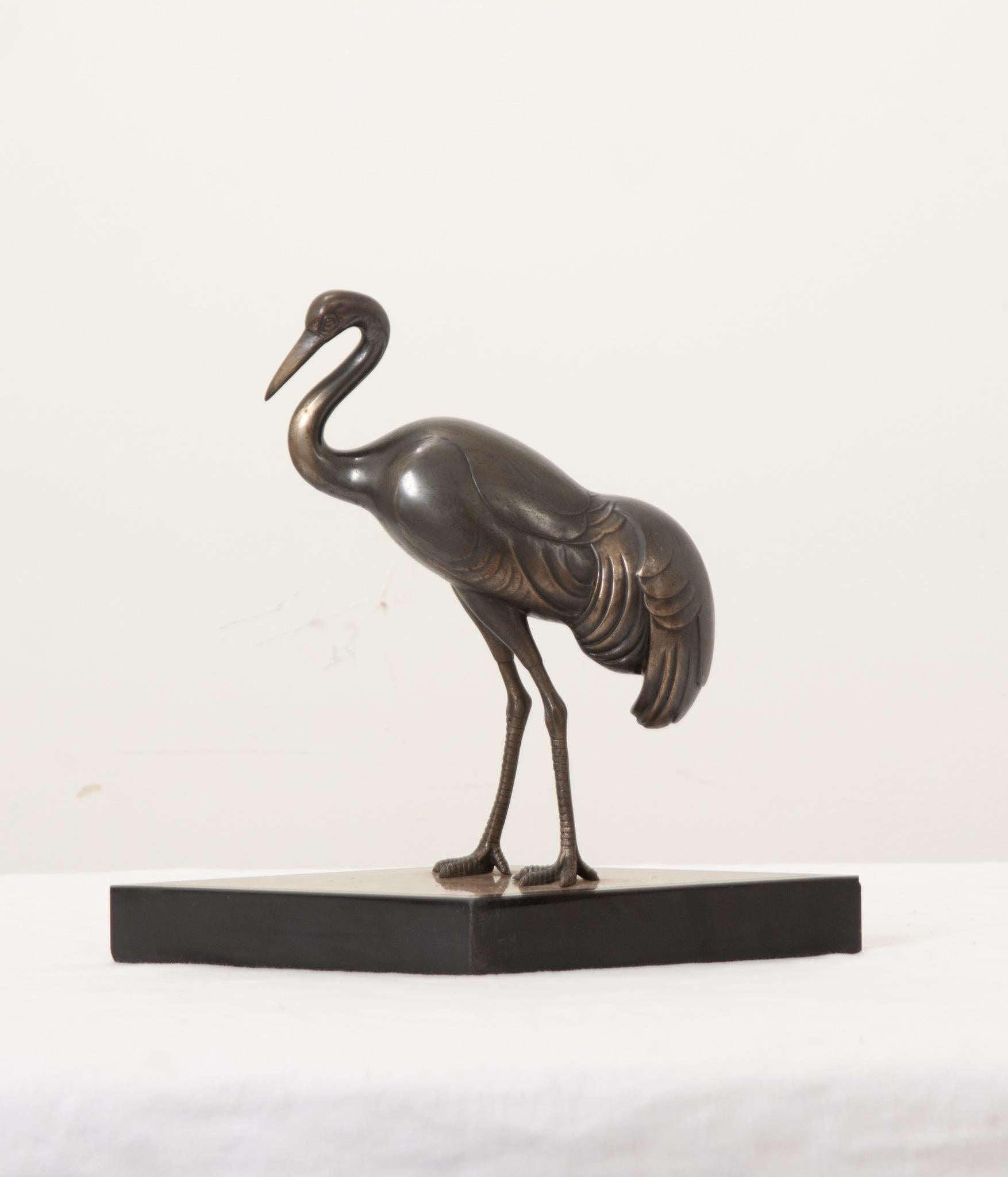 A petite statue of a bronze stork over a diamond shaped base made of travertine, surrounded in black marble. The perfect accessory to use anywhere in your interior. Be sure to view the detailed images to see the current condition of this mid-century