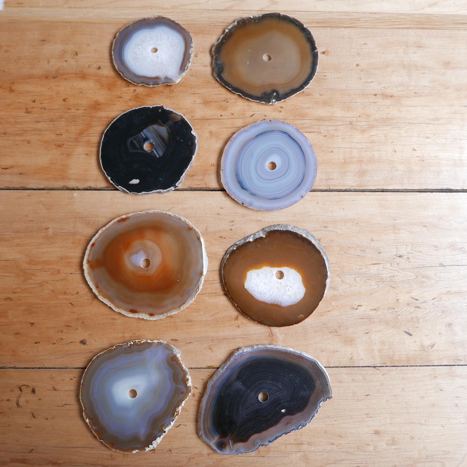 A set of natural stone circular drink place mats or coasters. Likely Agates.

France, c1970s.

A variety of colours and stone specimens.

All have a circular hole in the centre presumably to mount on a rod for storage. But said rod is