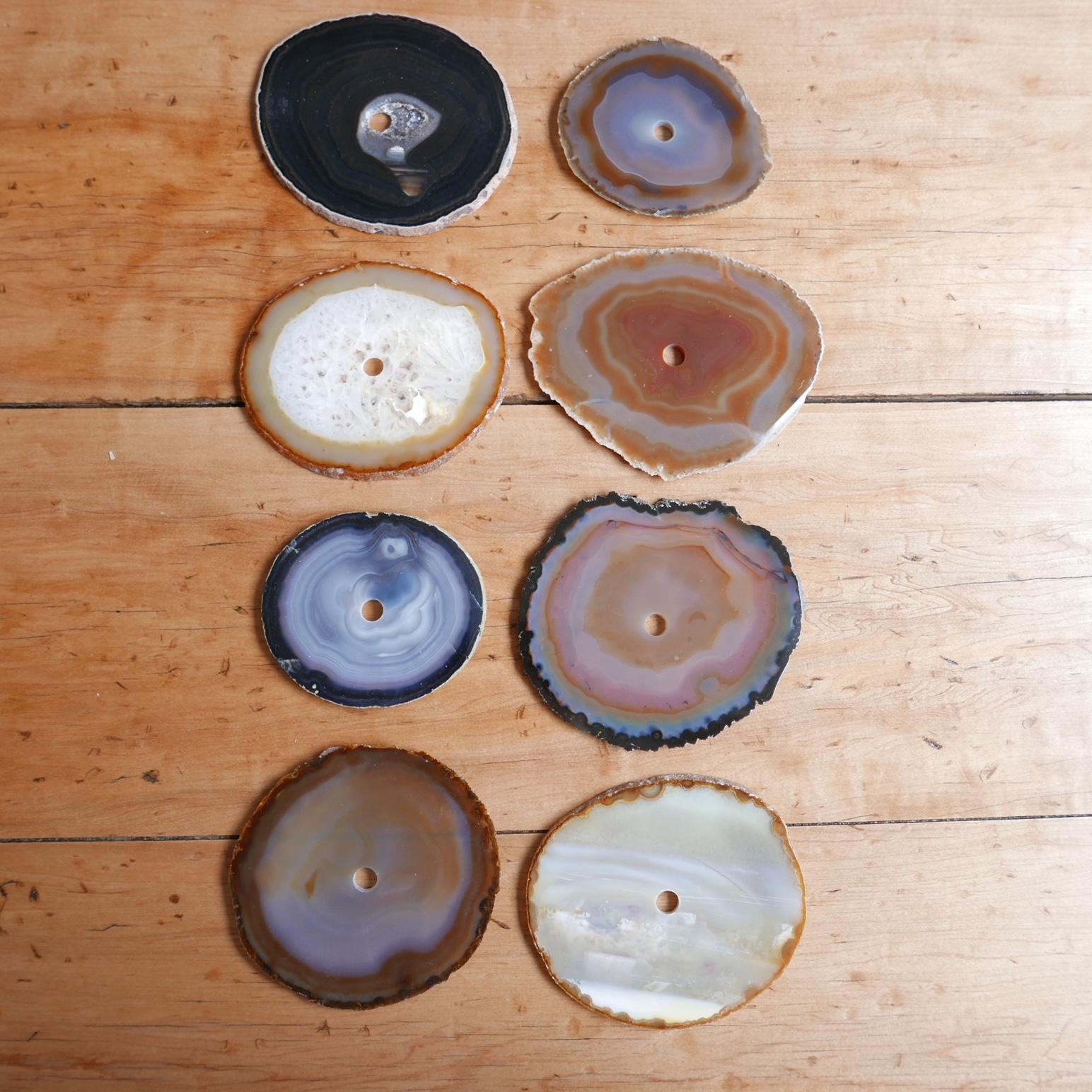 A set of natural stone circular drink place mats or coasters. Likely Agates. 

France, c1970s.

A variety of colours and stone specimens.

All have a circular hole in the centre presumably to mount on a rod for storage. But said rod is