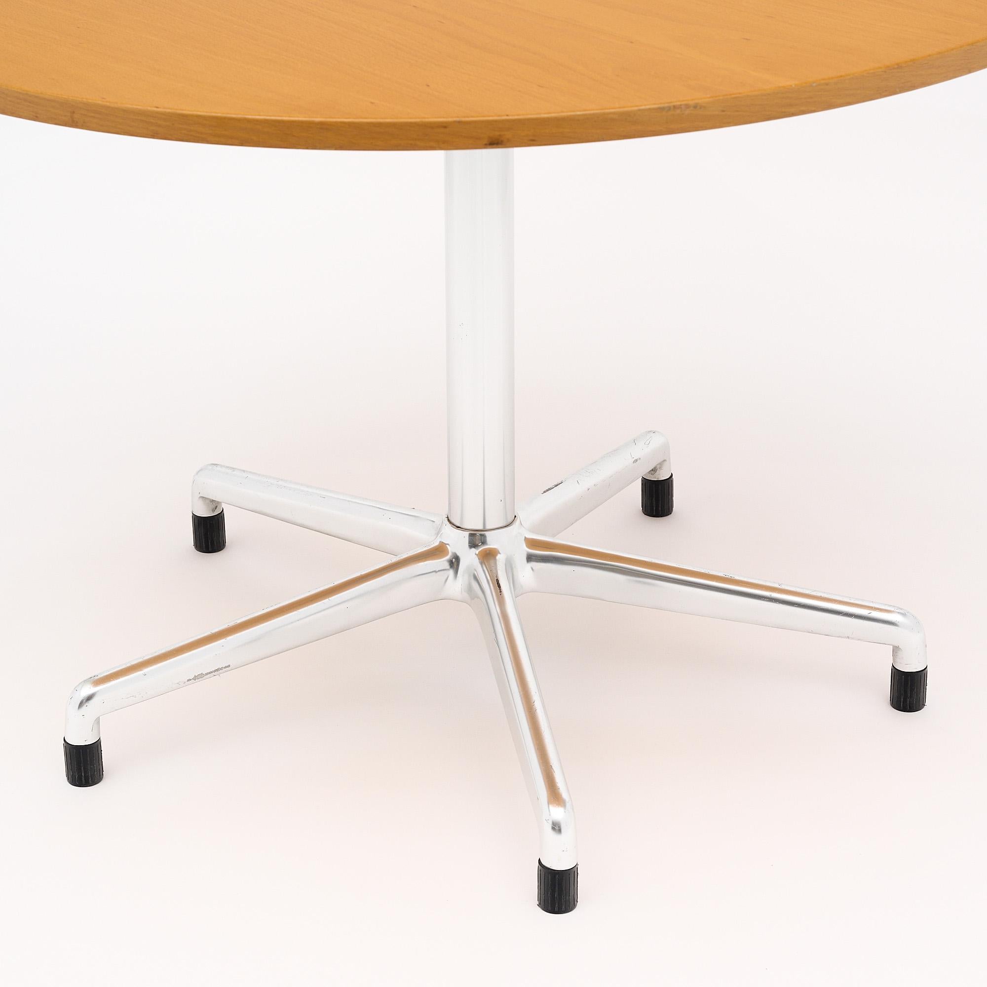 Round dinning table, French, in the manner of Knoll’s conference table design by Eames. This elegant table features a satin wooden top supported by a chromed steel center leg with five feet. The table top can flip for ease of movement and