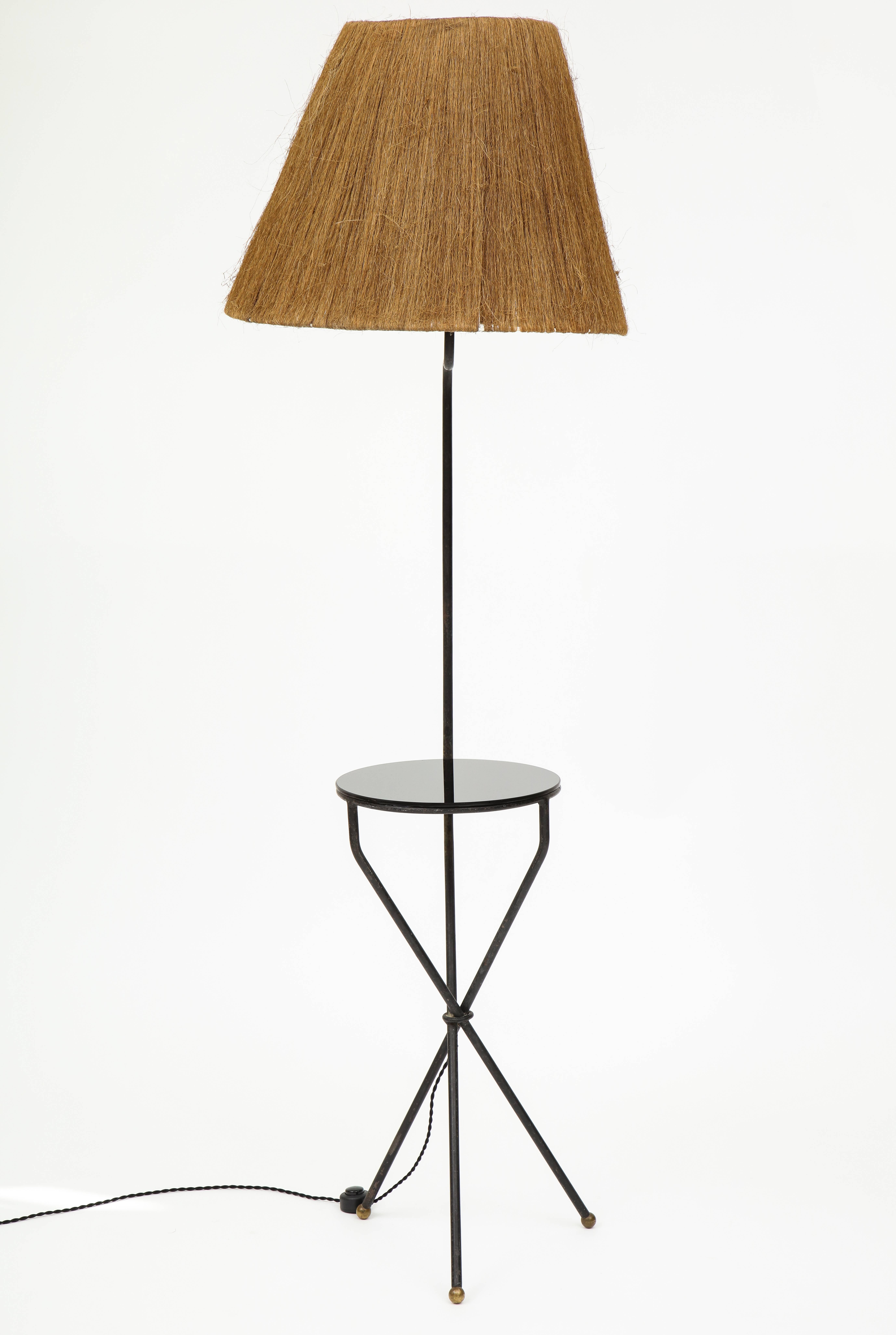 French tripod iron and glass black floor lamp with horsehair lampshade, 1950-1960

Beautiful floor lamp in original vintage condition. It is made out of iron and has detailed brass feet. The mirror table portion is black mirror. The lampshade is
