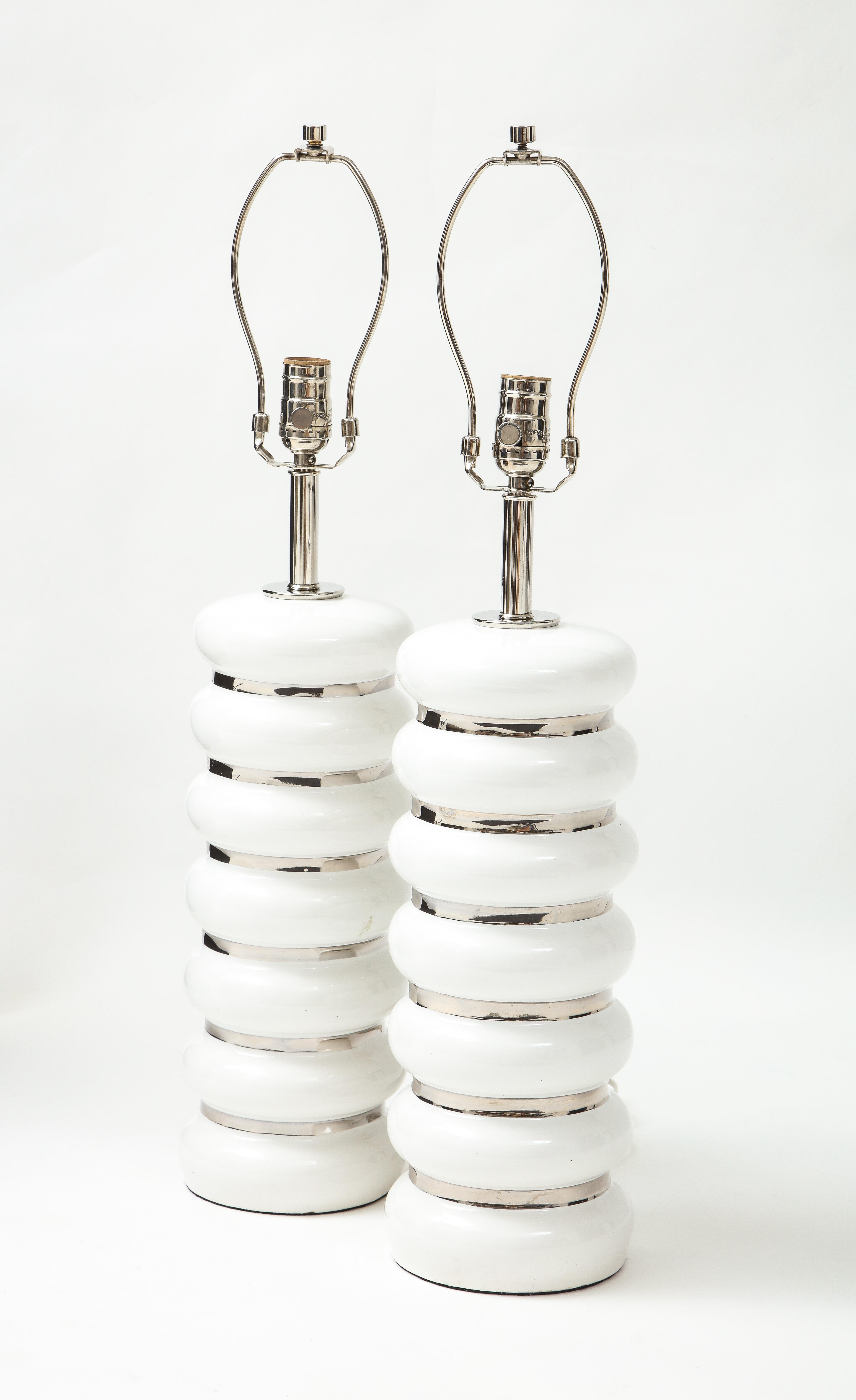 Pair of French Mid-Century Modern white porcelain lamps with hand applied platinum glaze stripes. Rewired for use in the USA using brushed nickel fittings, 100W max.