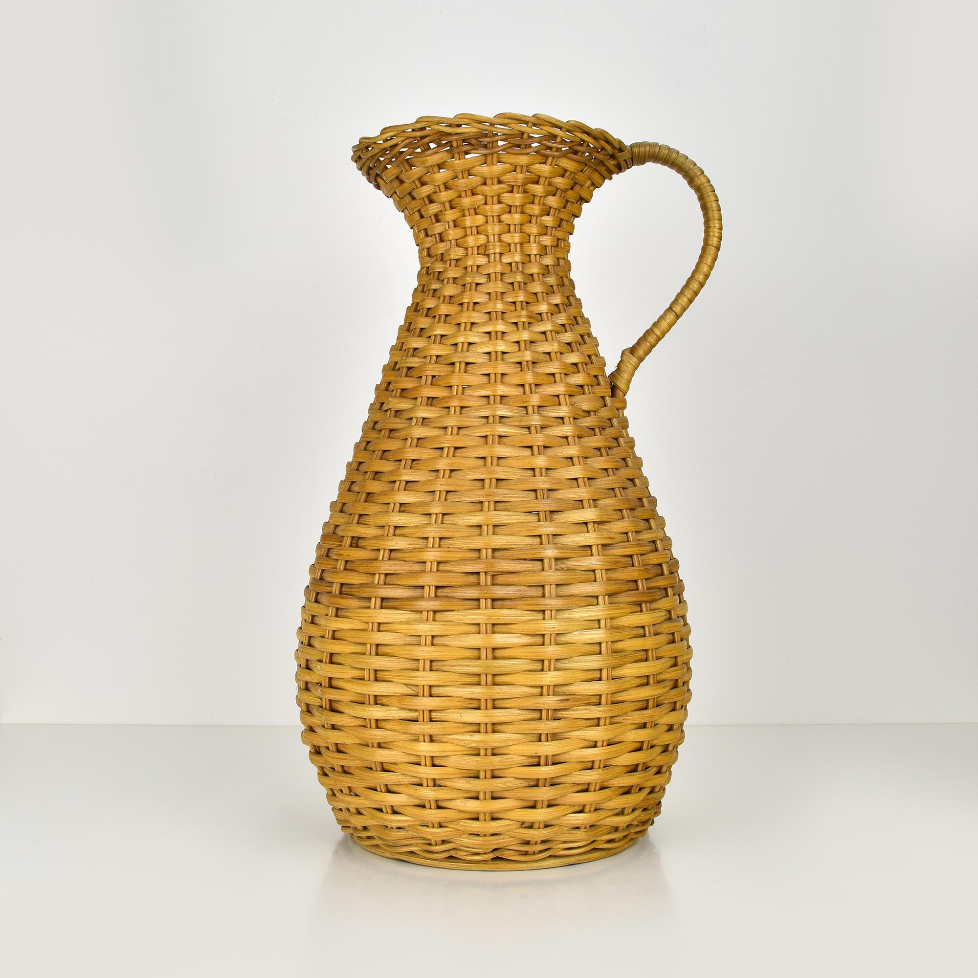 Questo affascinante vaso francese della metà del secolo scorso è finemente realizzato in rattan intrecciato, risalente agli anni Cinquanta. Il pezzo presenta un'elegante forma a balaustro con un collo svasato e un manico integrato, che mette in