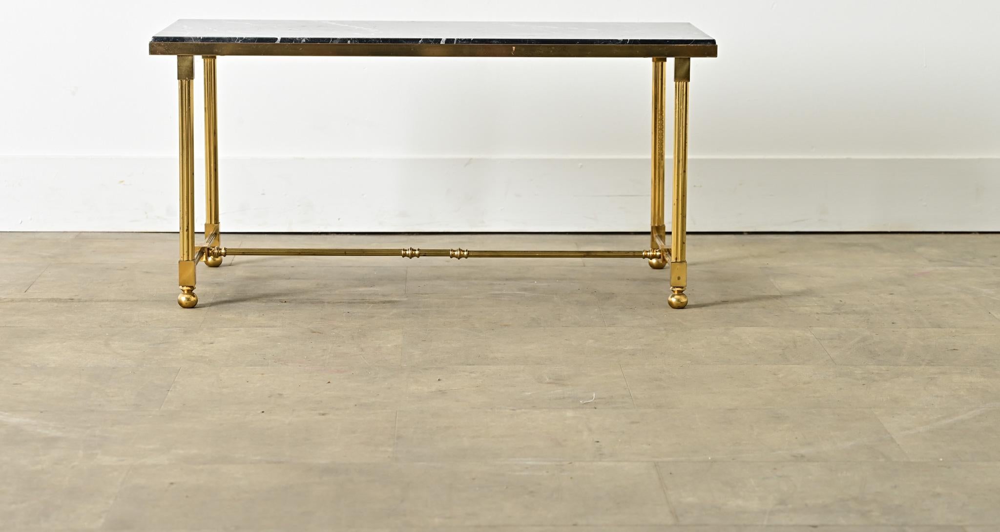 A vintage midcentury French brass and marble coffee/cocktail table in the style of legendary firm Maison Jansen reflecting the typical aesthetic codes of Hollywood Regency taste, given a few original twists to modernize the Neoclassical silhouette.