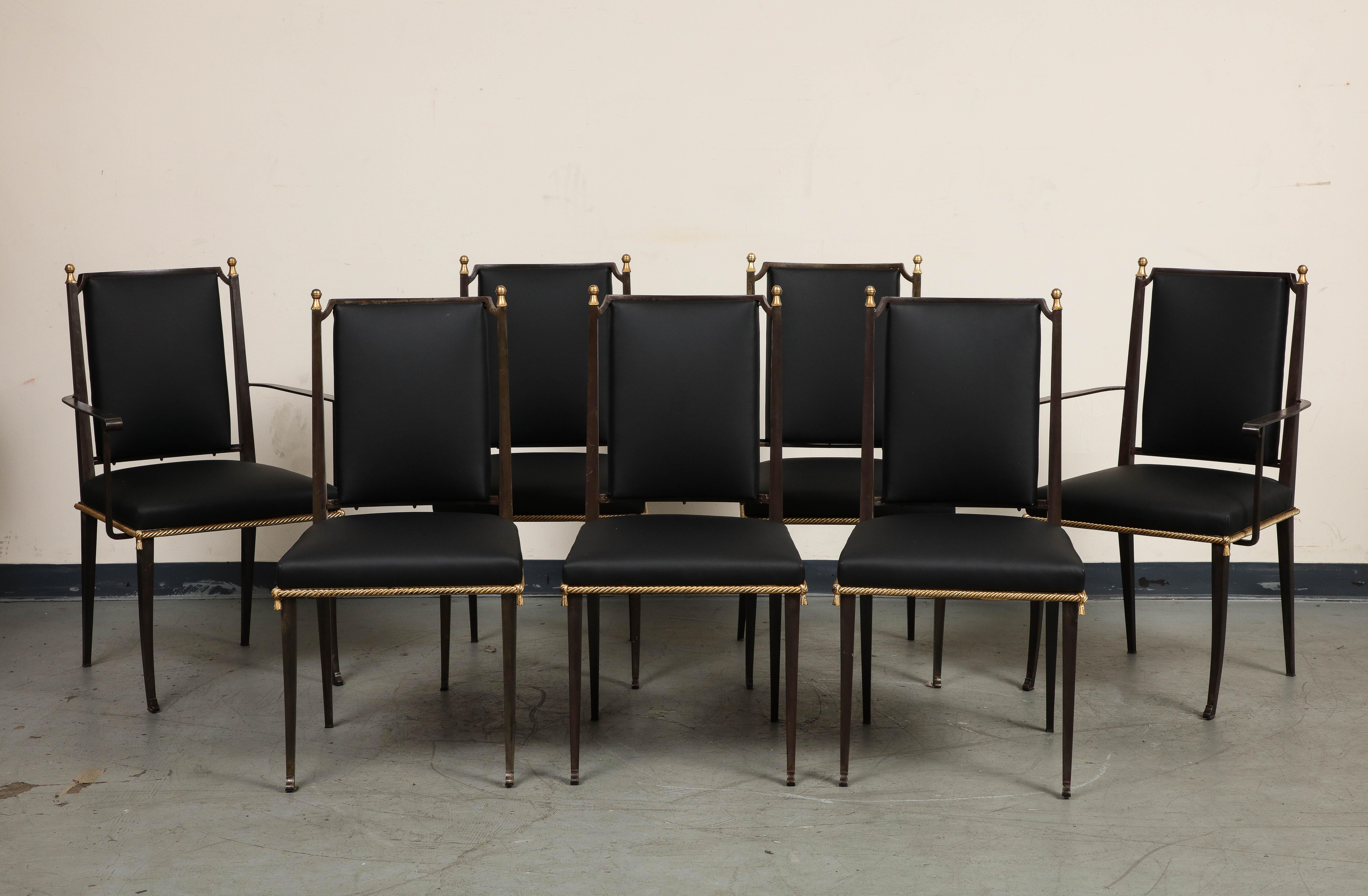 Ensemble de 7 chaises de salle à manger françaises du milieu du siècle avec des cadres en fer noirci et un nouveau revêtement en cuir noir. Les éléments dorés comprennent une garniture en forme de corde autour de l'assise, le bouton au centre du