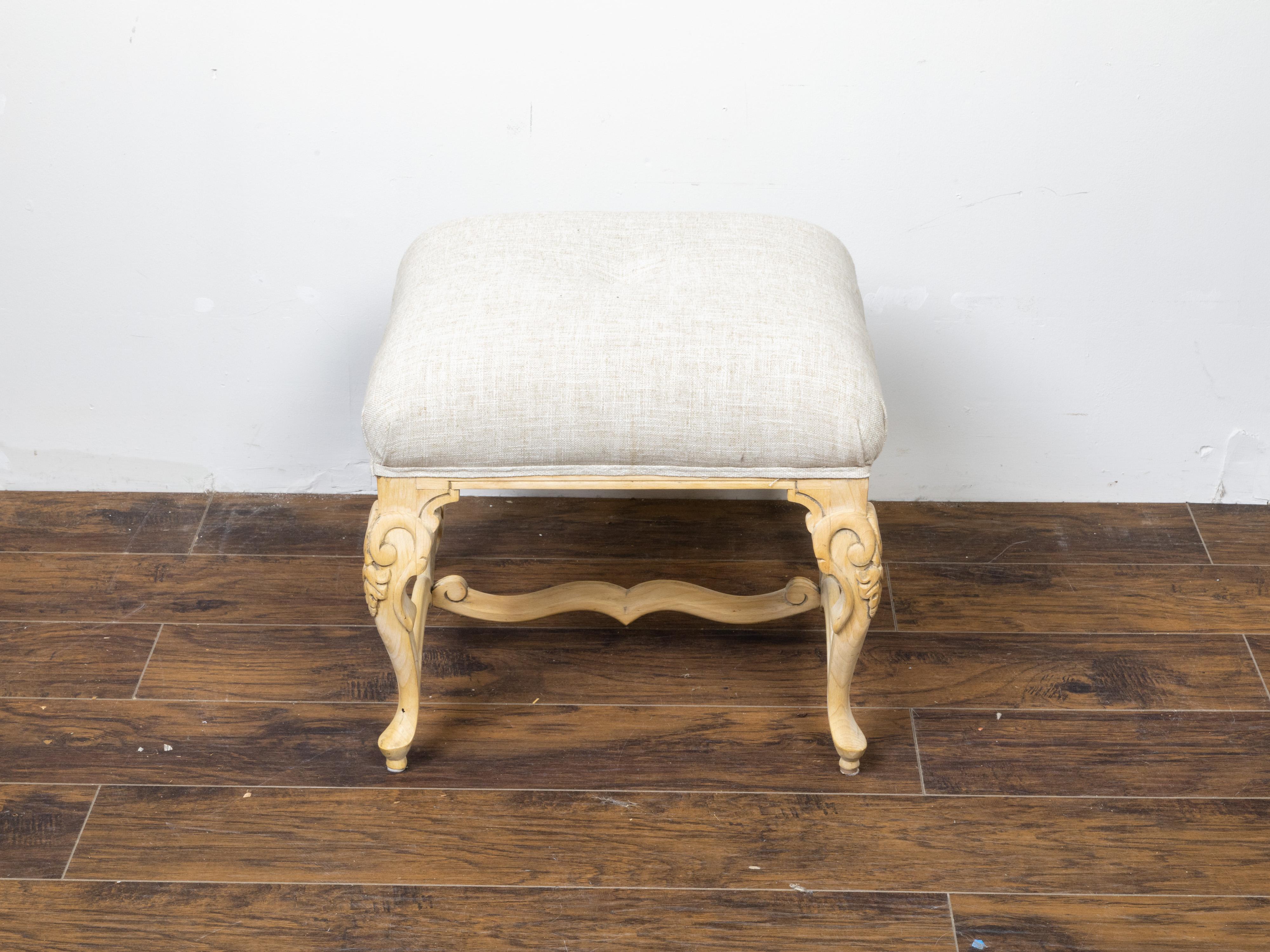 A French vintage bleached wooden stool from the mid 20th century, with carved legs and new upholstery. Created in France during the midcentury period, this bleached wood stool features a square seat newly reupholstered with a neutral toned linen