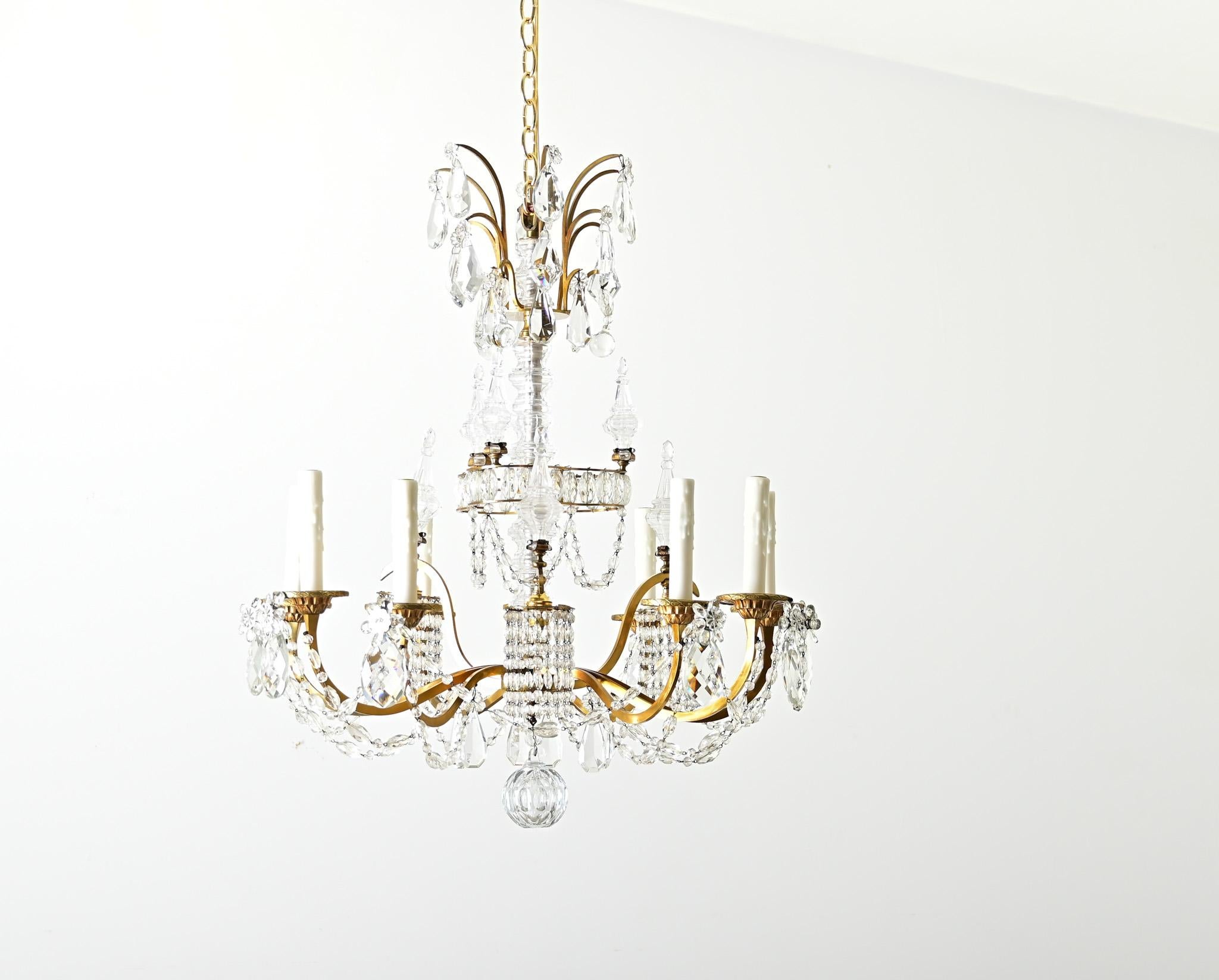 Un lampadario in ottone e cristallo francese della metà del XX secolo con dodici fonti di luce per illuminare la tua sala da pranzo, il tuo foyer o un altro grande spazio. Questo lampadario in stile Maison Baguès ha una struttura in ottone che è