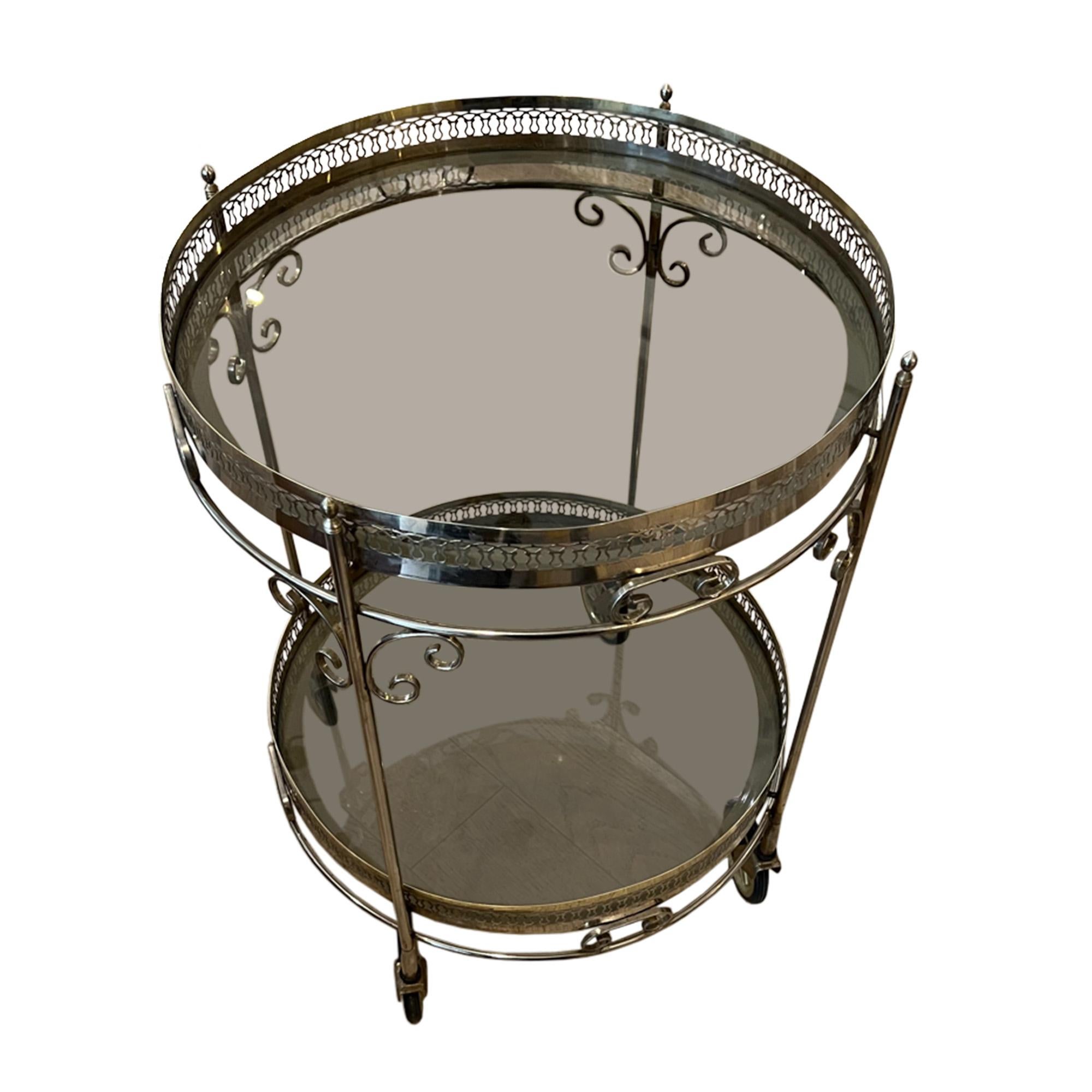 This unusual mid century bar cart was made in France in the 1960s - please take a look at all the pictures to see a close up on the finials and detail on the metal work.

The glass is slightly smoked and the brass patina is more silver than gold.