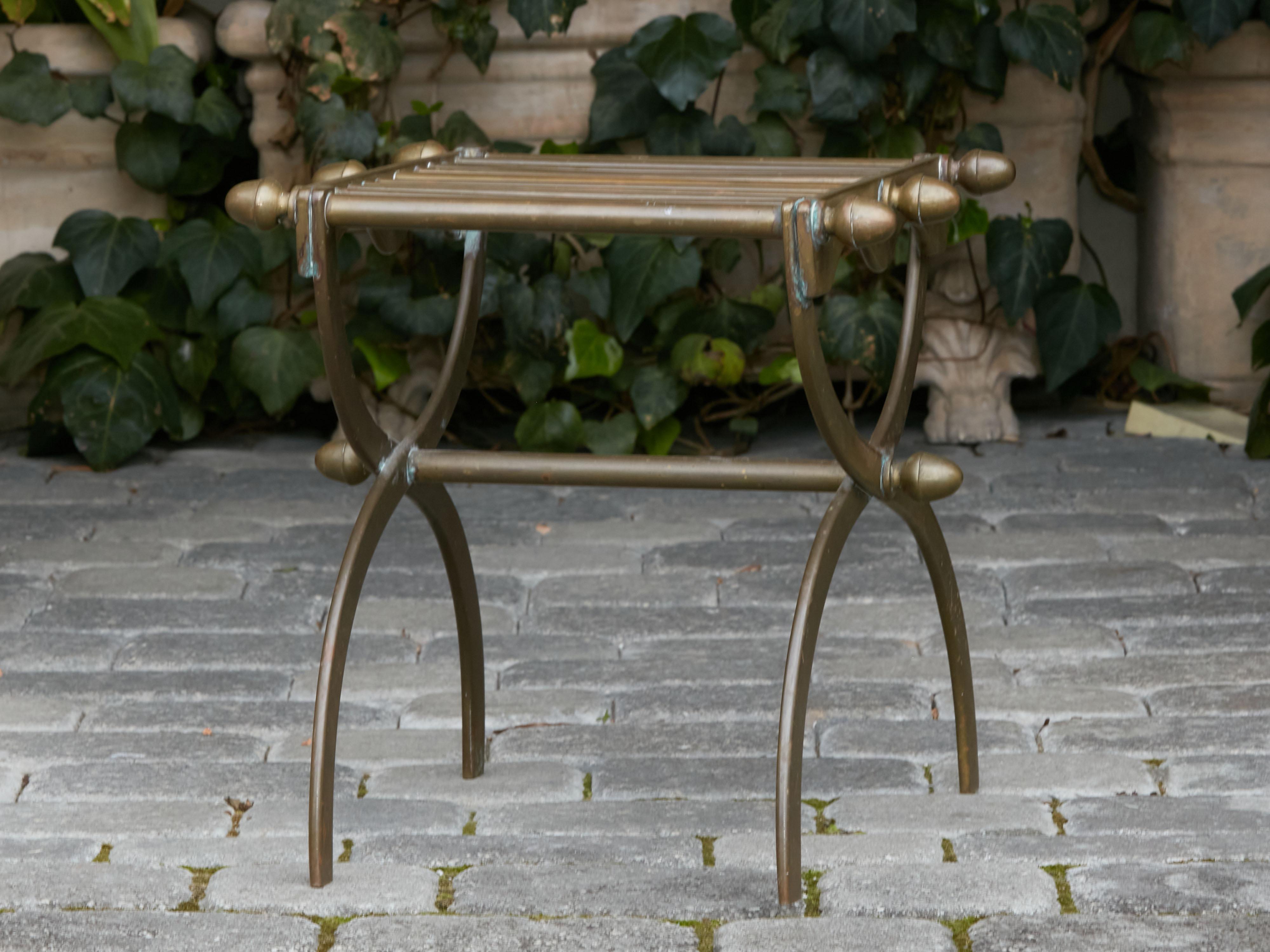 A French bronze stool from the mid 20th century with double X-Form base. Created in France during the Midcentury period, this bronze stool features a stick top with acorn style accents on the sides, resting above a double X-Form base with cross