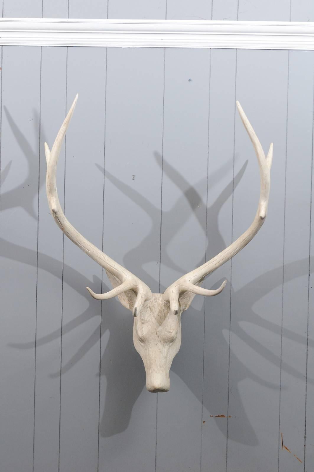 A French carved and painted wood deer head sculpture from the mid-20th century, with large antlers. This French deer head sculpture exudes a striking presence. The nicely detailed surface along with the expressive face are perfectly emphasized by