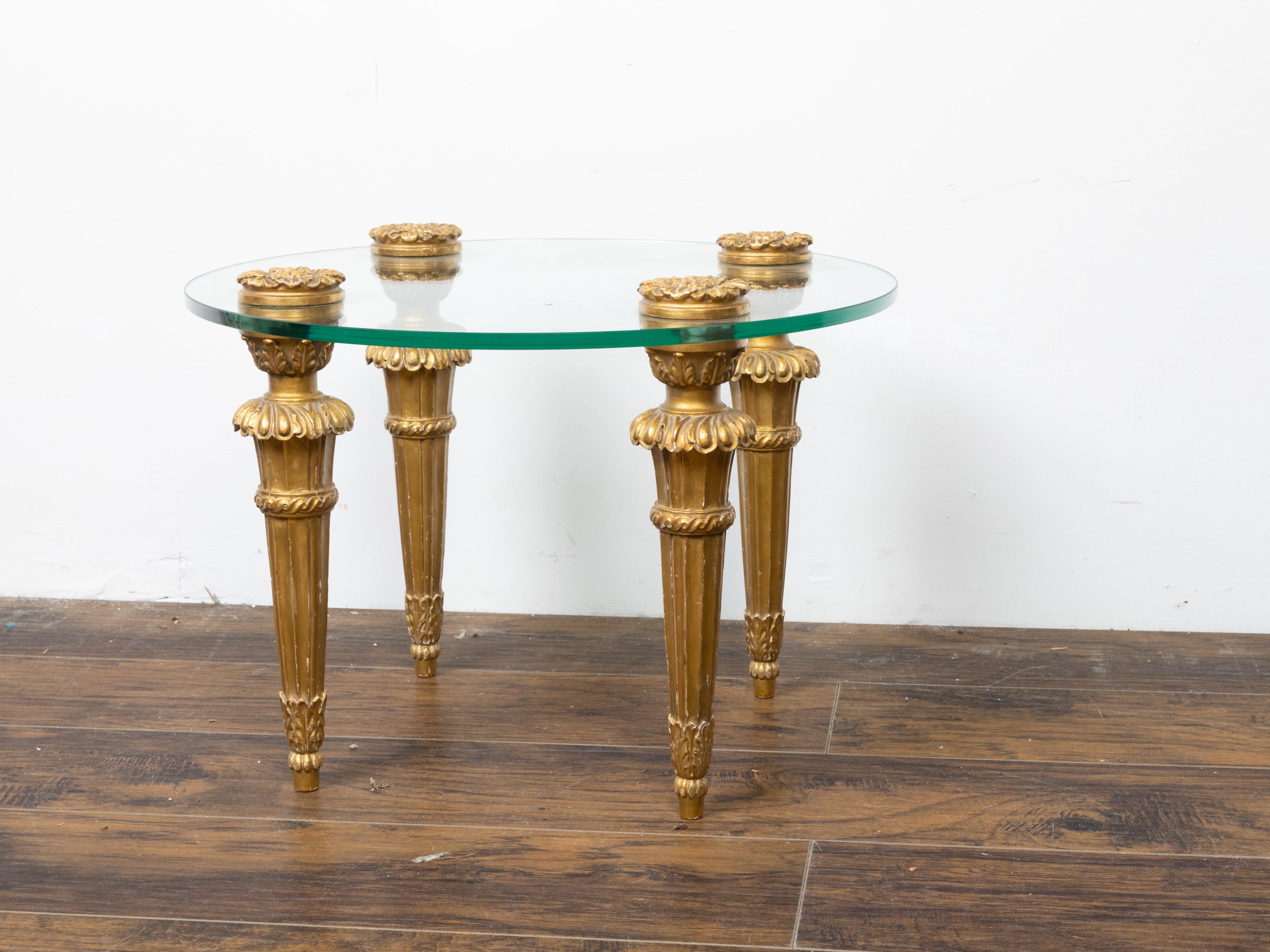 Table de cocktail en bois doré sculpté du milieu du 20e siècle, avec plateau en verre et rosettes. Créée en France au milieu du siècle dernier, cette petite table à boire présente un plateau circulaire en verre reposant sur une base en bois doré