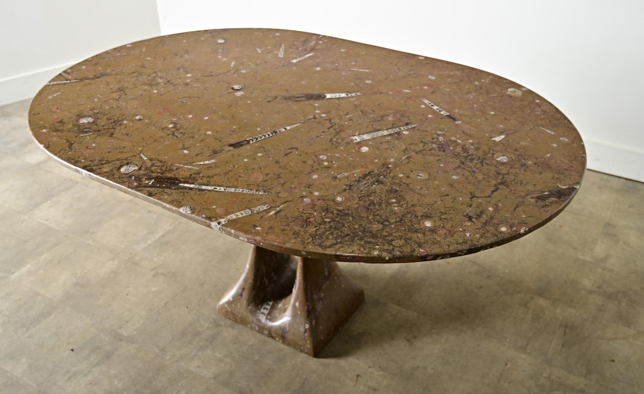Fabulous vintage French dining table of circa 1970, carved from a unique block of Moroccan marble populated by the fossilized remains of a variety of marine life. Dagger-shaped belemnite fossils (dating to at least 65 million years old) are