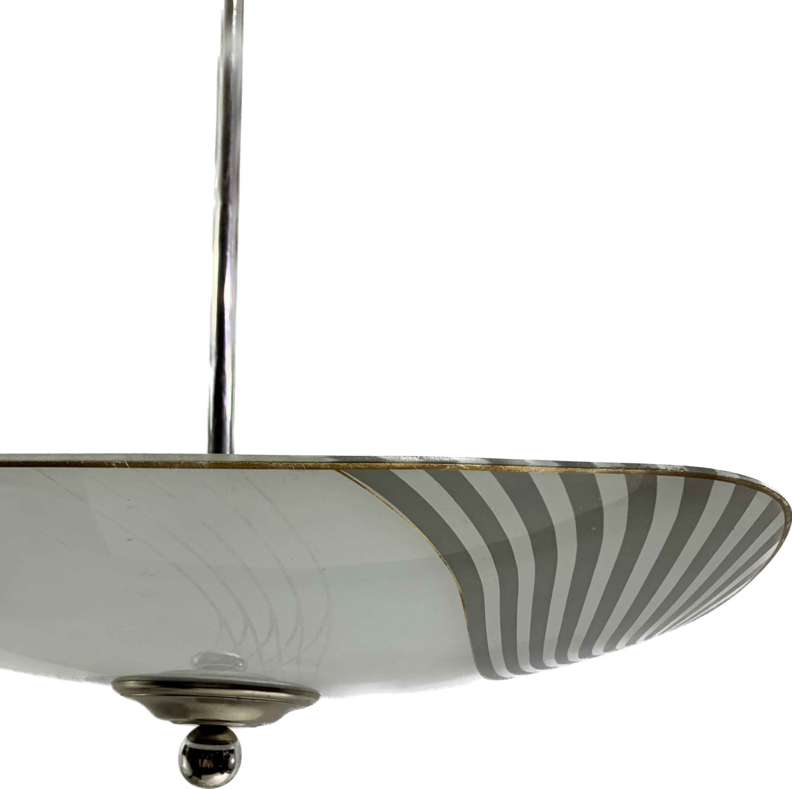 French Art Deco modernist pendant light. The structure is in nickel plated metal. The glassware has black drawings, representing geometric wavy patterns all around the lampshade. This pendant light is typical of the modernists’ Art Deco Movement, it