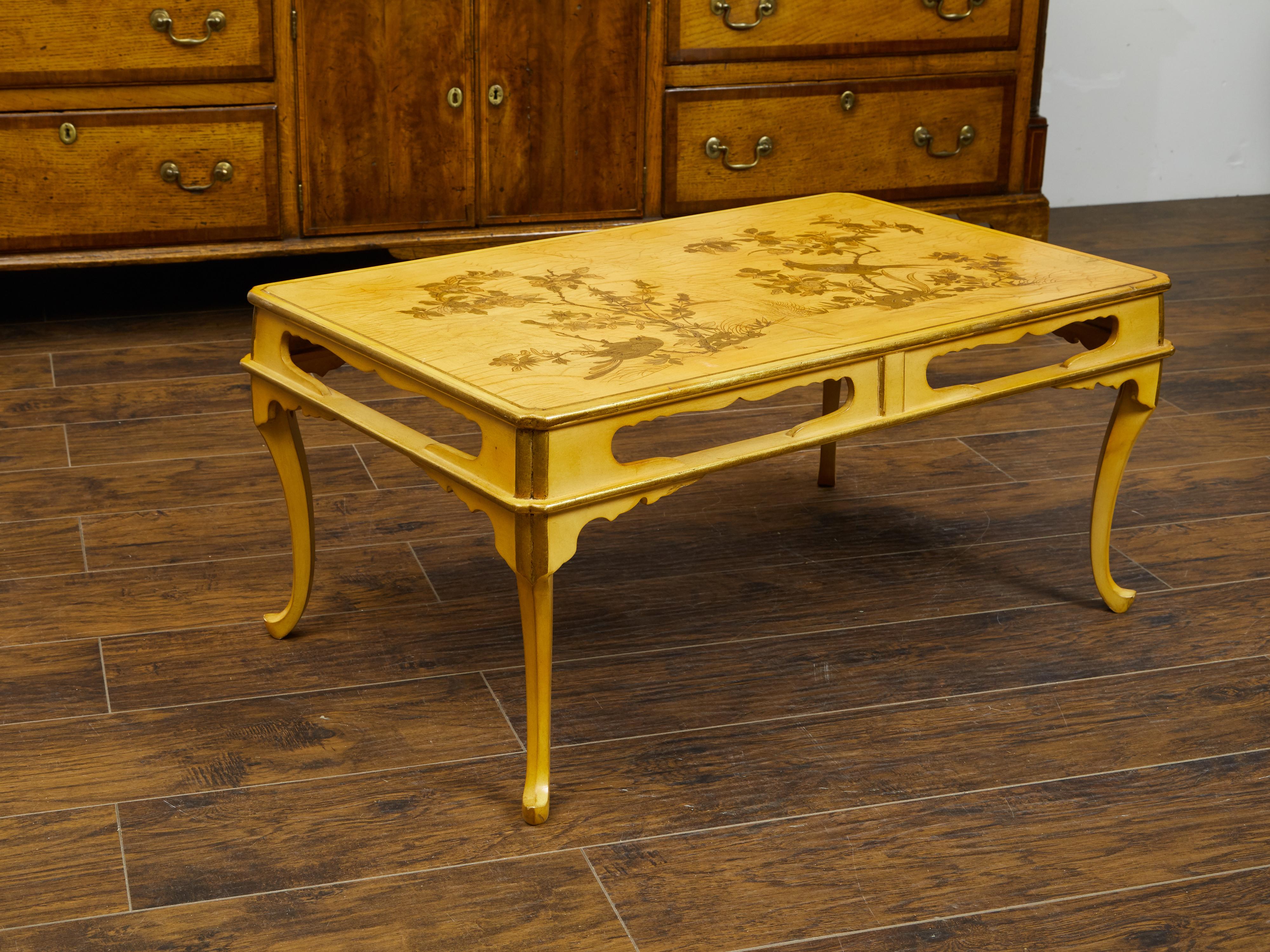 A French chinoiserie style coffee table from the mid 20th century, with birds and foliage. Created in France during the midcentury period, this coffee table charms us with its delicate chinoiserie décor adorning the top. Two birds are perched on the
