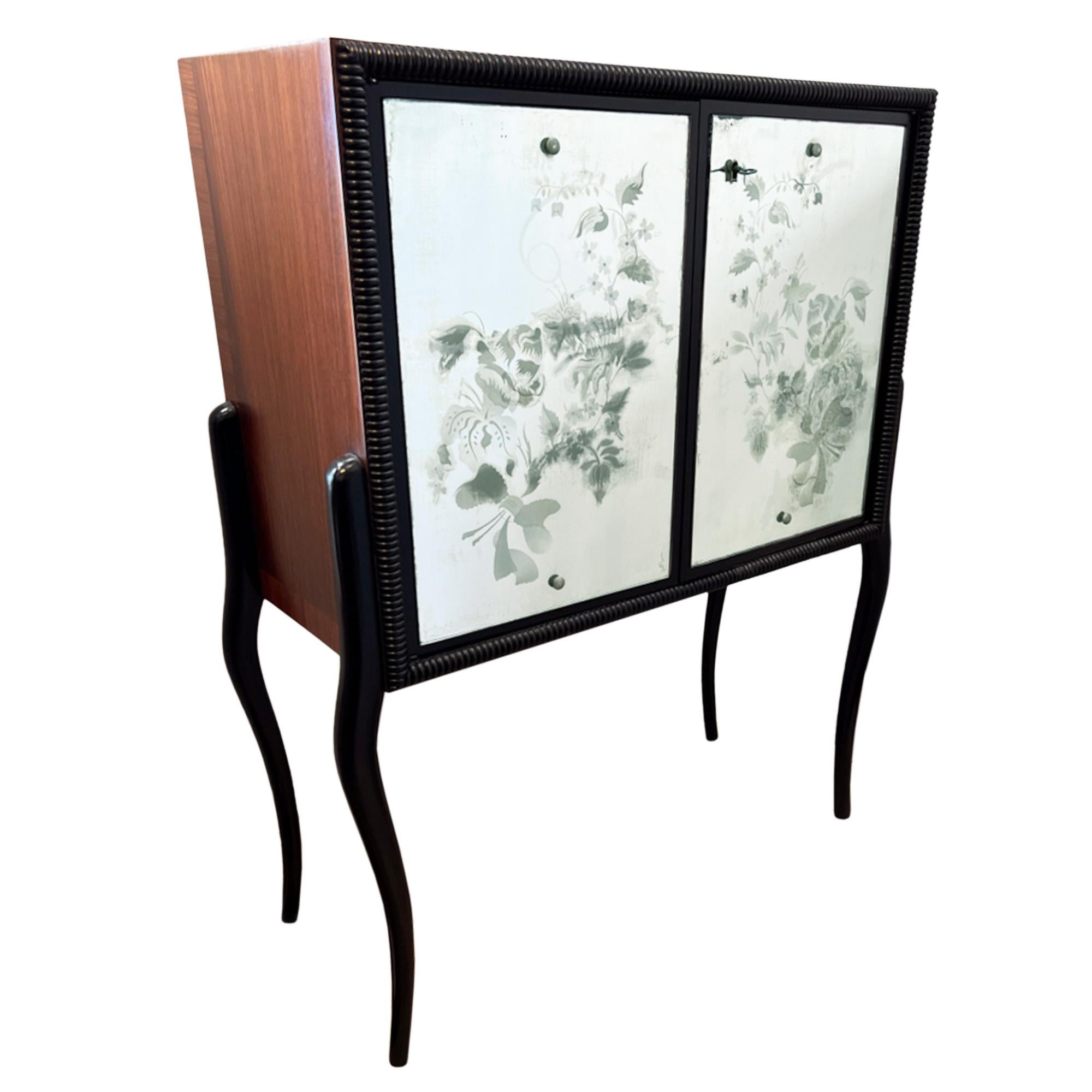 This is a really stylish cocktail cabinet. Made in France in the 1950s, it's crafted from hardwood veneer, ebonised beech and eglomise glass.

The decorative eglomise glass on the doors has a floral design and the interior has a red and gold