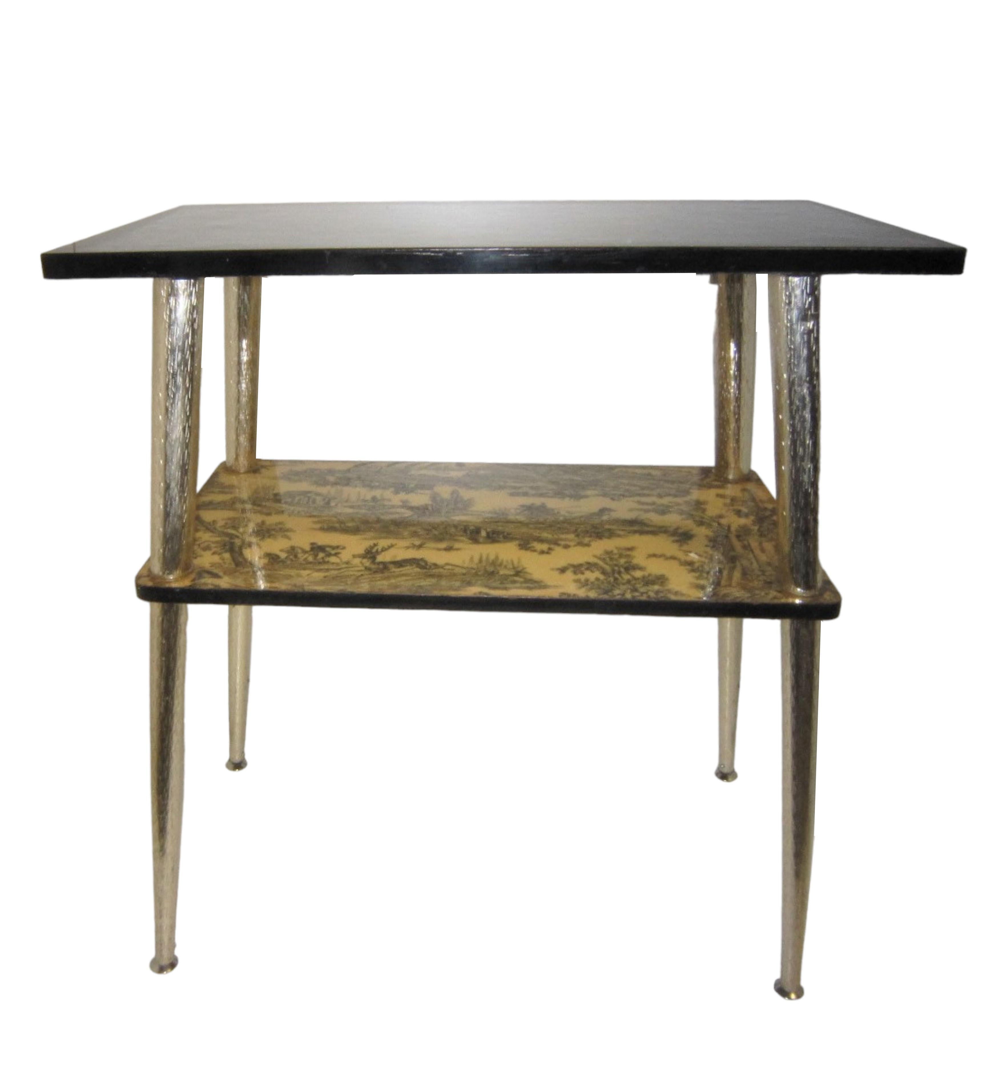 A French midcentury serving table featuring a black top depicting a hunting scene on second tier; the whole raised on slender tapering satin nickel metal legs with a hammered pattern.
The stretcher shelf is inspired by Toile, a French word meaning