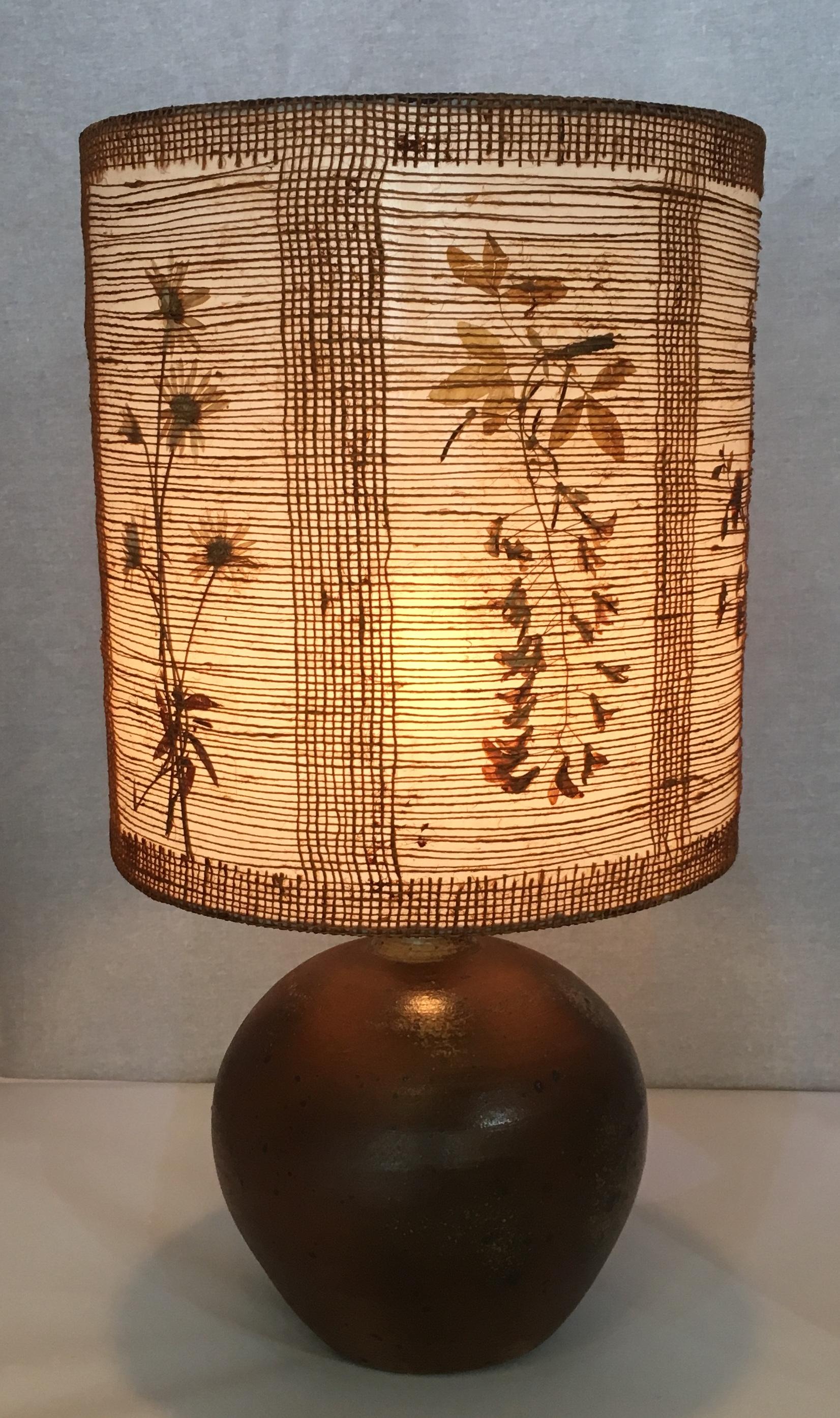 Very decorative midcentury table lamp in a stunning handcrafted shade decorated with dried flowers and leaves. The beige and light brown hues makes this piece very pleasing to the eye and its neutral tones are perfect for any design setting.