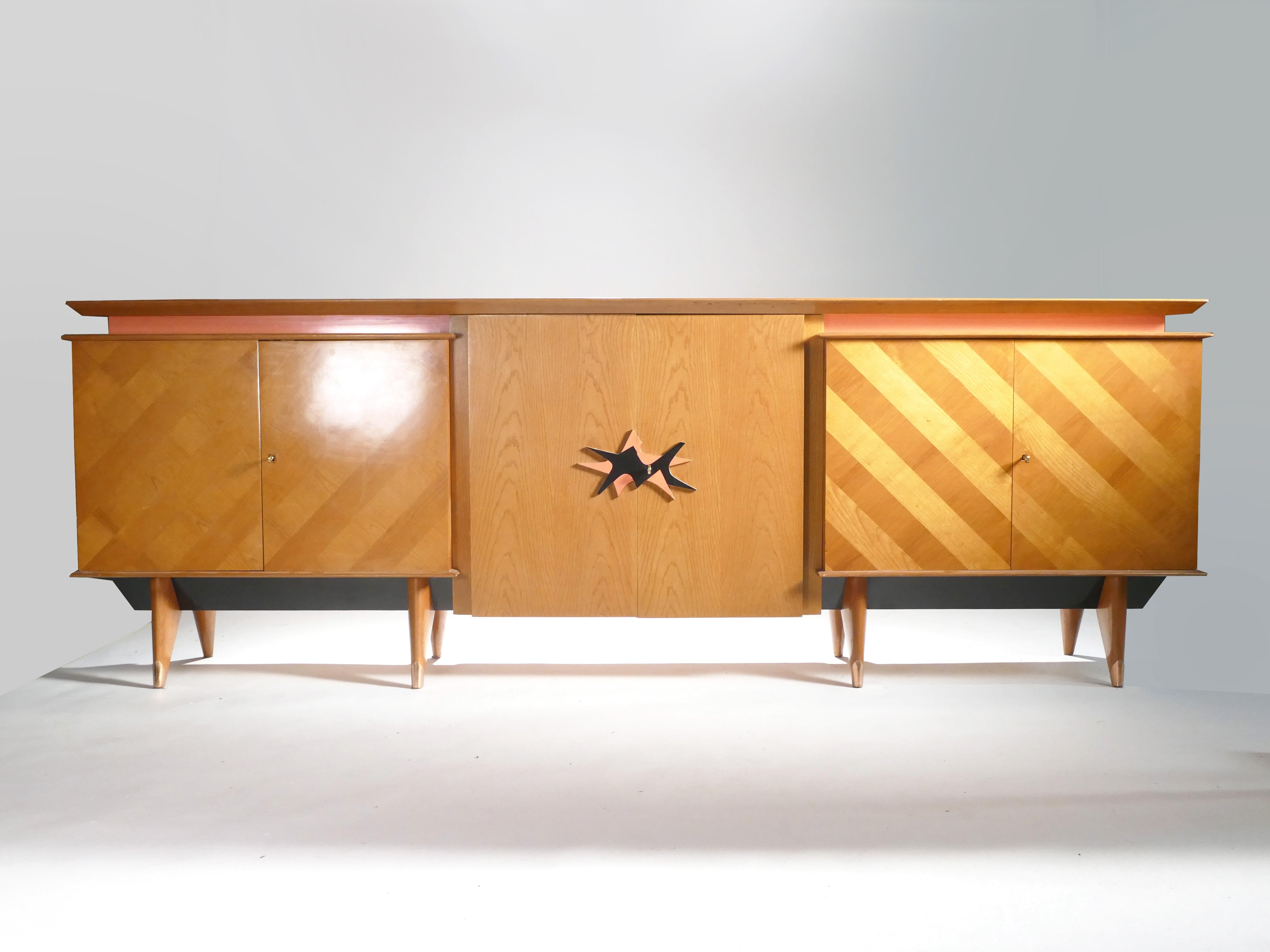 This attractive sideboard features a smooth oak build and bright copper accents. Monumental in size. The eye-catching coral and black decorative knobs on the centre cabinets, along with the contrasting wood stripes on the sideboard’s exterior, make