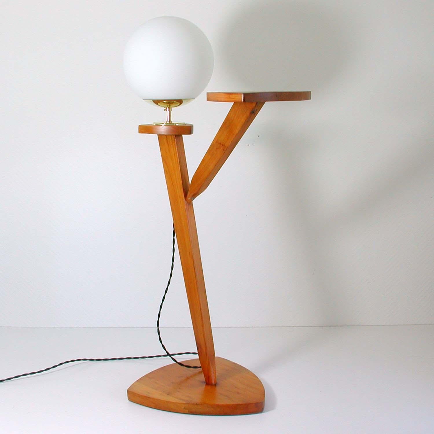 This vintage floor gueridon combo light was made in France in the 1950s. It is made of wood, has got a white opal glass lampshade and brass details. It can be used as a plant stand, a side table or an end table.

Rewired with new fabric wiring and