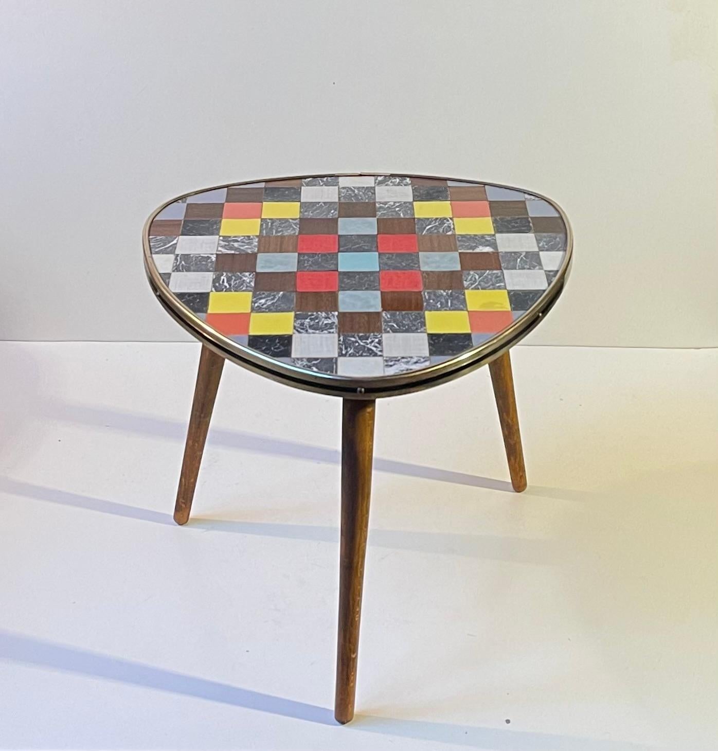 Petite table d'appoint créative ou porte-fleurs reposant sur trois pieds effilés et présentant un plateau en mosaïque façonné à partir de carrés de linoléum. Il a été fabriqué en France à la fin des années 1950 ou au début des années 1960. Les pieds