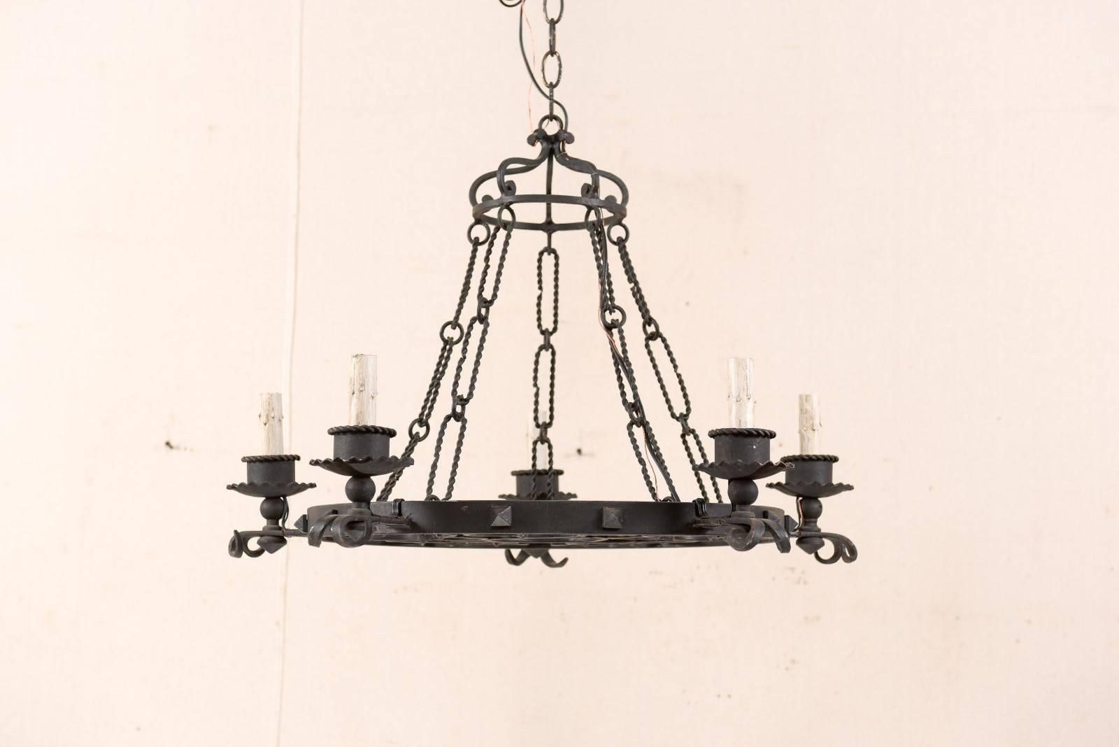 A French forged iron chandelier from the mid-20th century. This French mid-century chandelier features a circular ring with center design, facing downward, are segmented areas divided from the five light arms, each with a four leaf clovers. Five