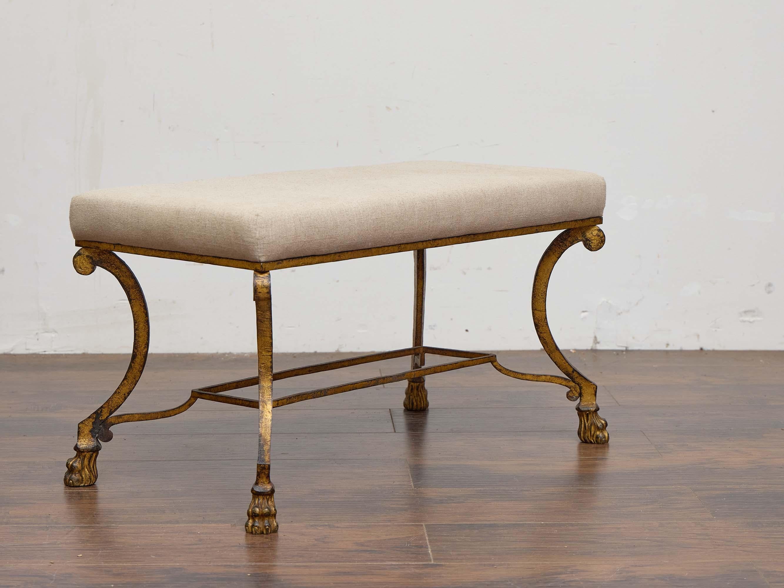 Questa panca francese della metà del secolo scorso presenta una graziosa silhouette in ferro dorato forgiato a mano con una classica decorazione a volute e piedi a zampa. Le eleganti gambe a forma di X si curvano verso l'interno con una raffinatezza