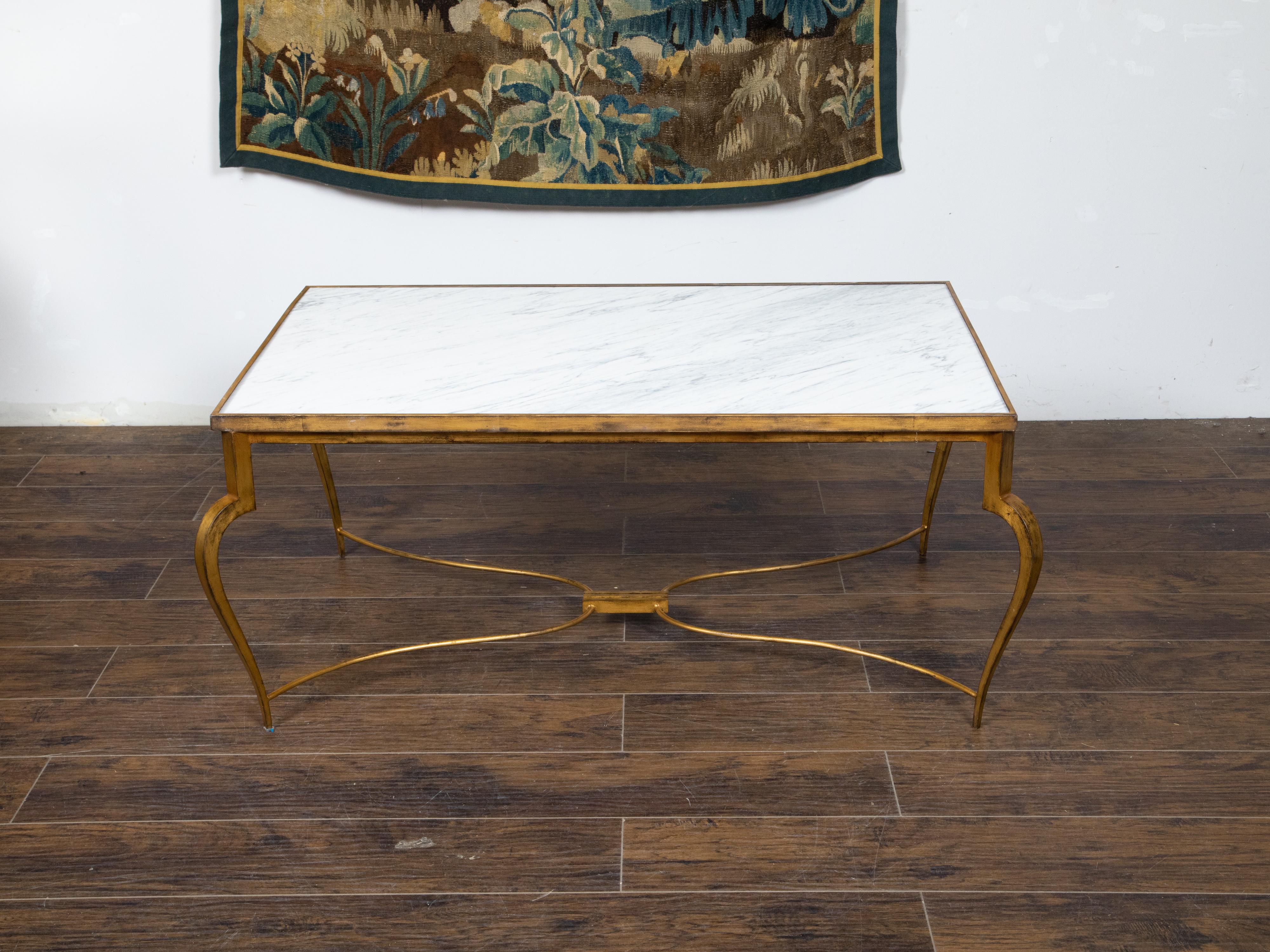 A French vintage gilt iron coffee table from the Mid-20th Century with white veined marble top, cabriole legs and curving X-Form stretcher. Created in France during the midcentury period, this coffee table features a rectangular white veined marble