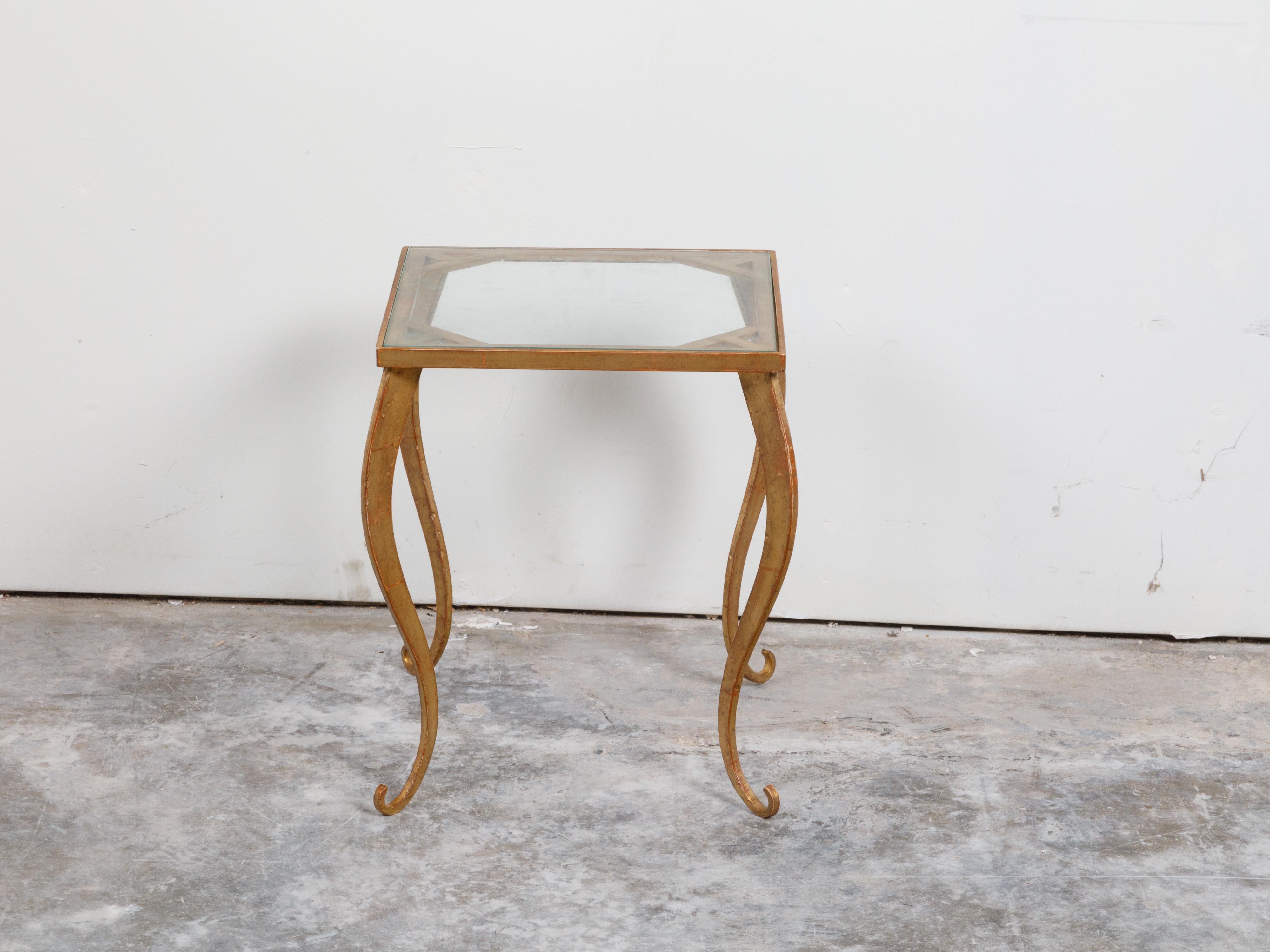 Une table d'appoint vintage en métal doré français du milieu du 20e siècle, avec plateau en verre et pieds cabriole. Créée en France au milieu du siècle dernier, cette table d'appoint en métal doré est dotée d'un plateau en verre carré reposant sur