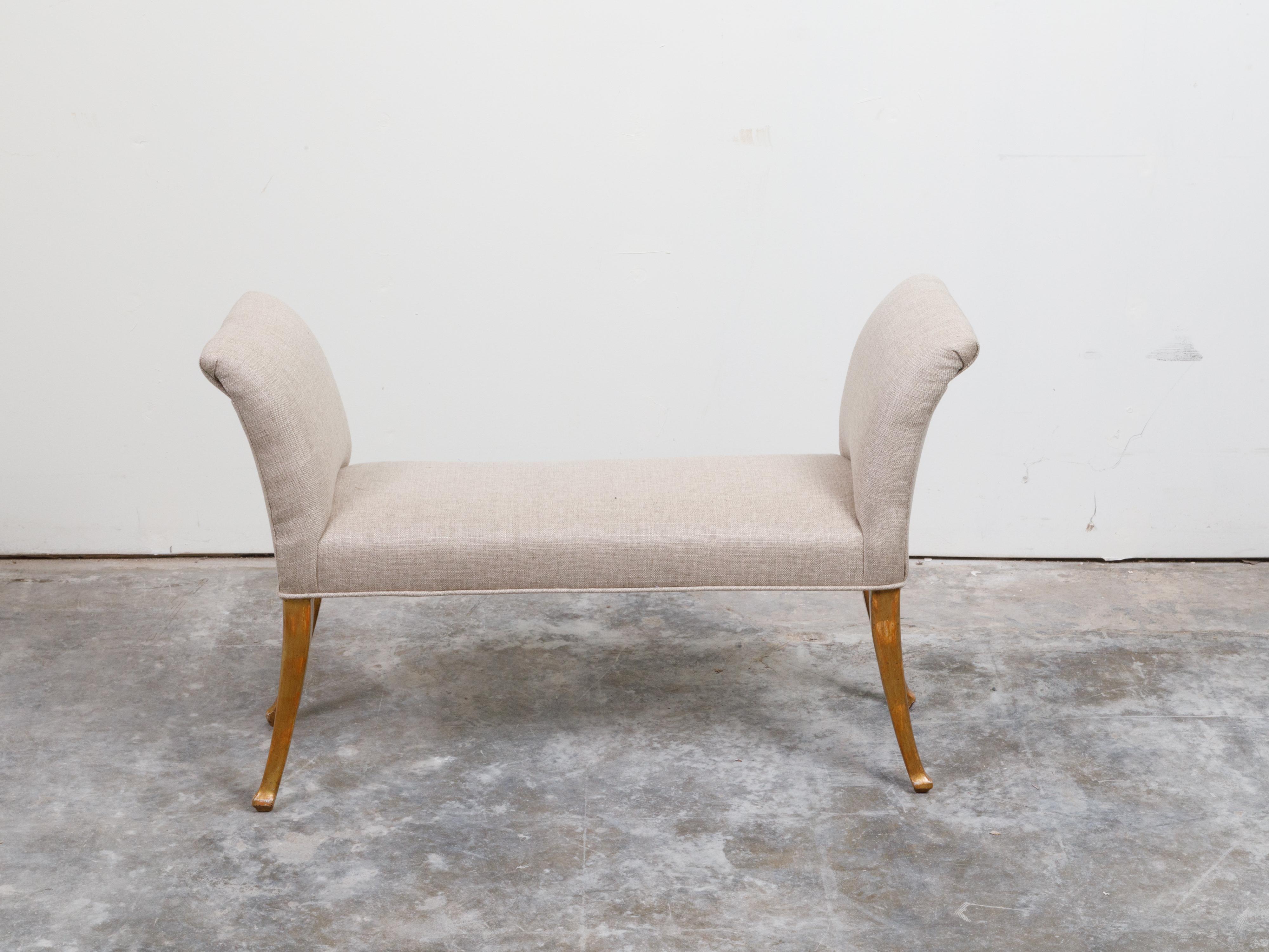 A French giltwood bench from the mid 20th century, with out-scrolling arms, saber legs and new upholstery. Created in France during the mid-century period, this window bench features two out-scrolling arms flanking a rectangular seat, all newly