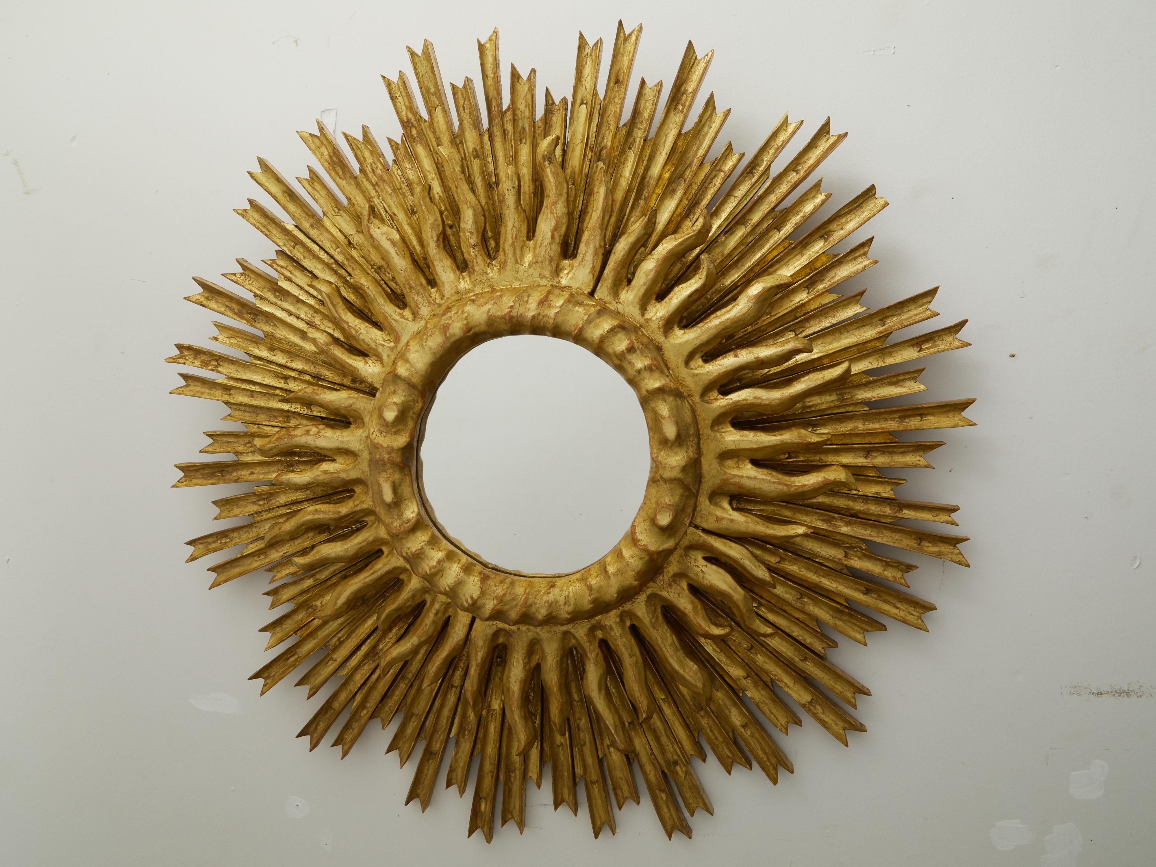 Französischer vergoldeter Sonnenschliffspiegel aus der Mitte des 20. Jahrhunderts, mit geschichteten Strahlen und kleiner Spiegelplatte. Dieser um die Jahrhundertmitte in Frankreich geschaffene Sunburst-Spiegel weist eine zentrale Spiegelplatte auf,