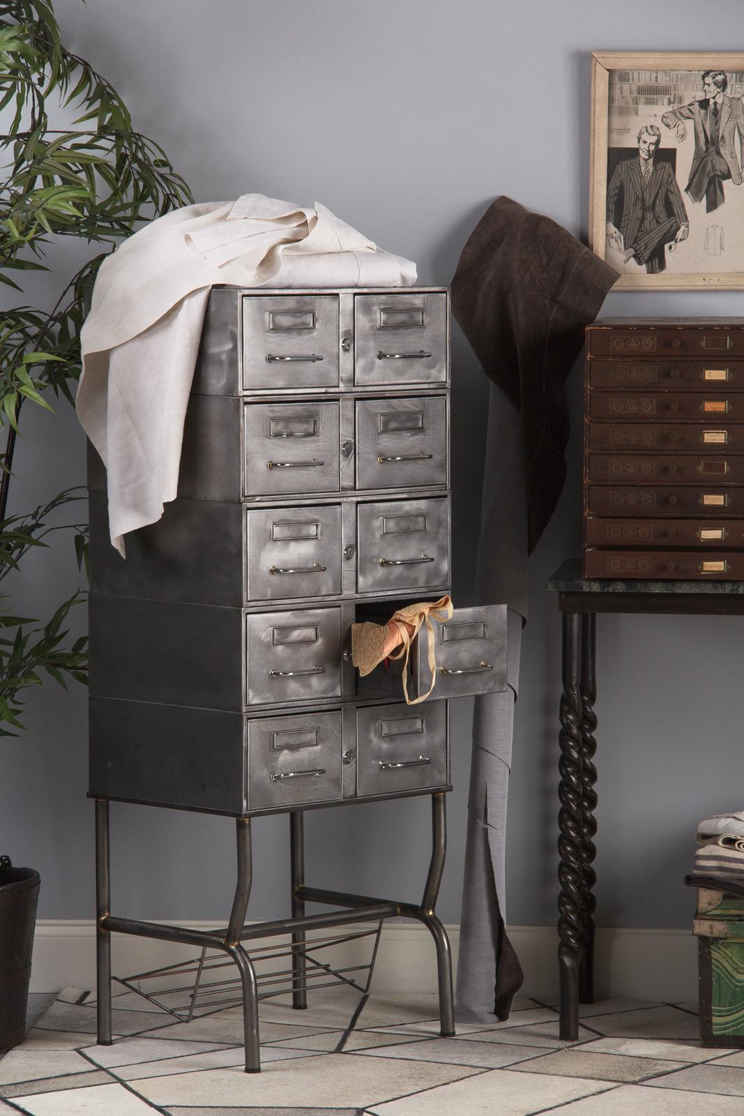 A tall Industrial polished steel file cabinet on an open base, French midcentury. Ten drawers in two columns are housed in a handsome polished steel case perched over a four legged base with a wire shelf built in. The cabinet is in three parts, with