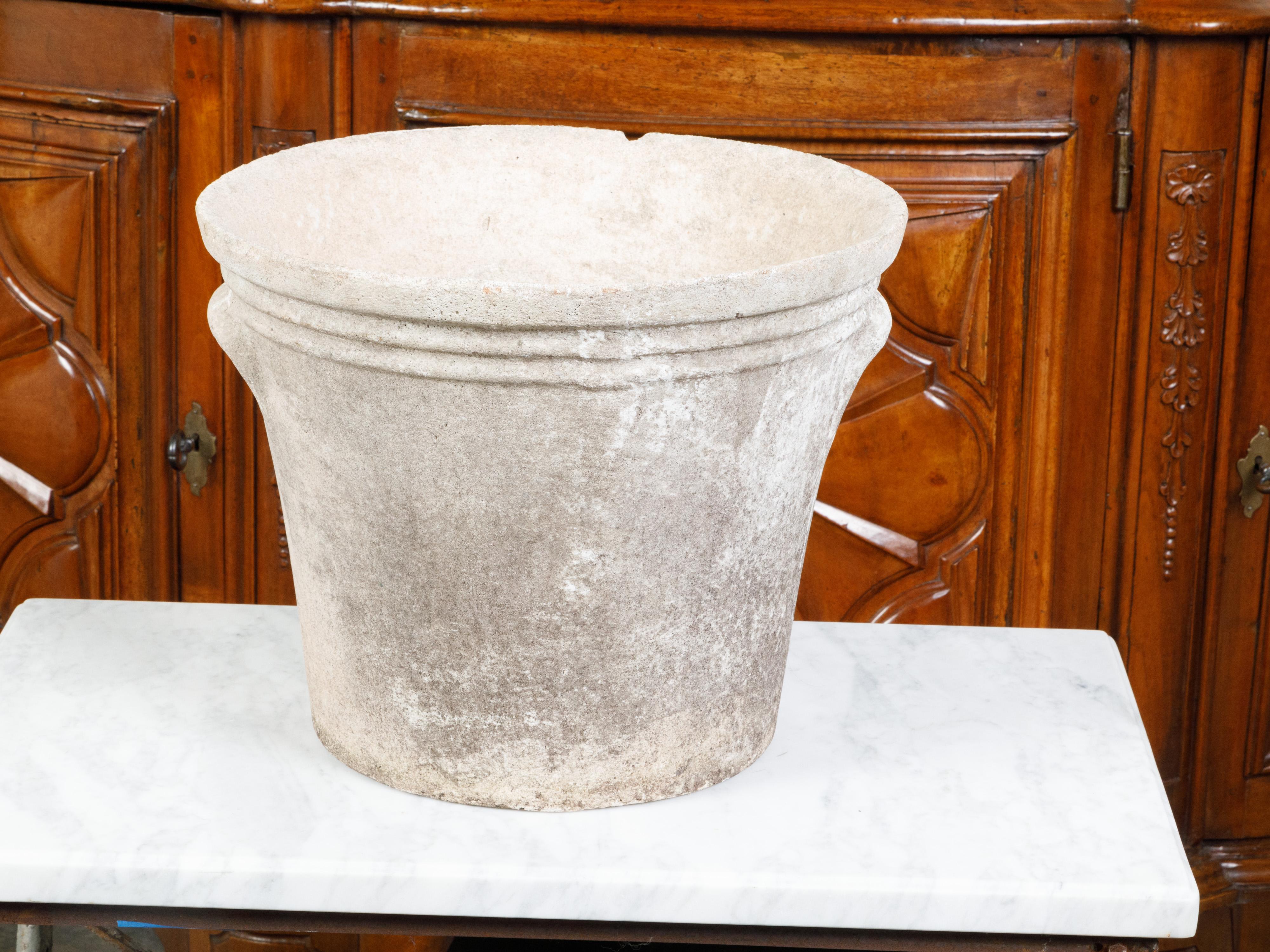 A vintage French planter from the mid 20th century, with decorative handles and patina. Created in France during the Midcentury period, this planter features a circular tapering body (the base measuring 11.5