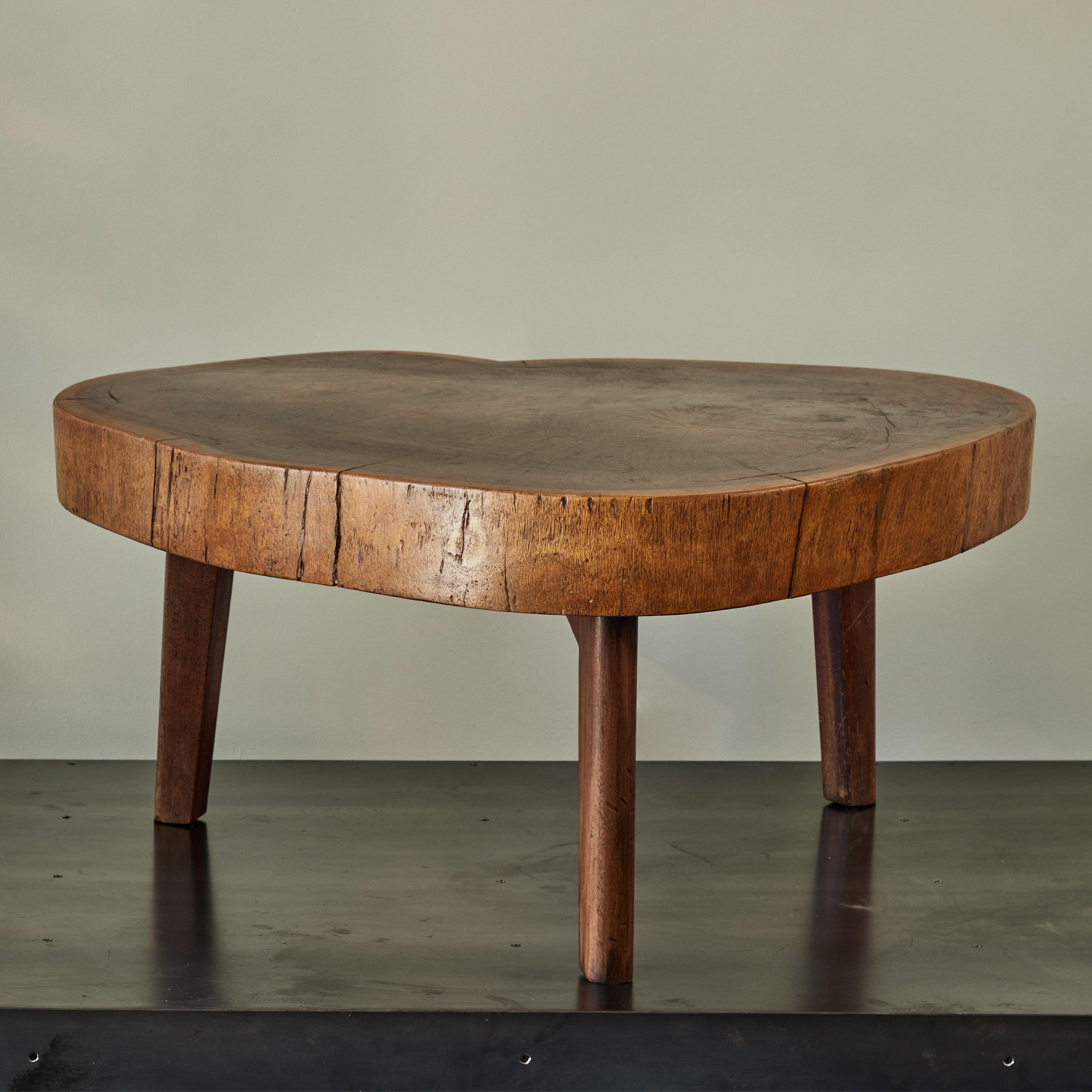 French mid-century live edge wood coffee table in a ruddy chestnut hue, set atop three slightly tapered walnut legs. The design has a swank naturalism that is both warm and inviting.

France, circa 1950

Dimensions: 42.5W x 42D x 19.5H.