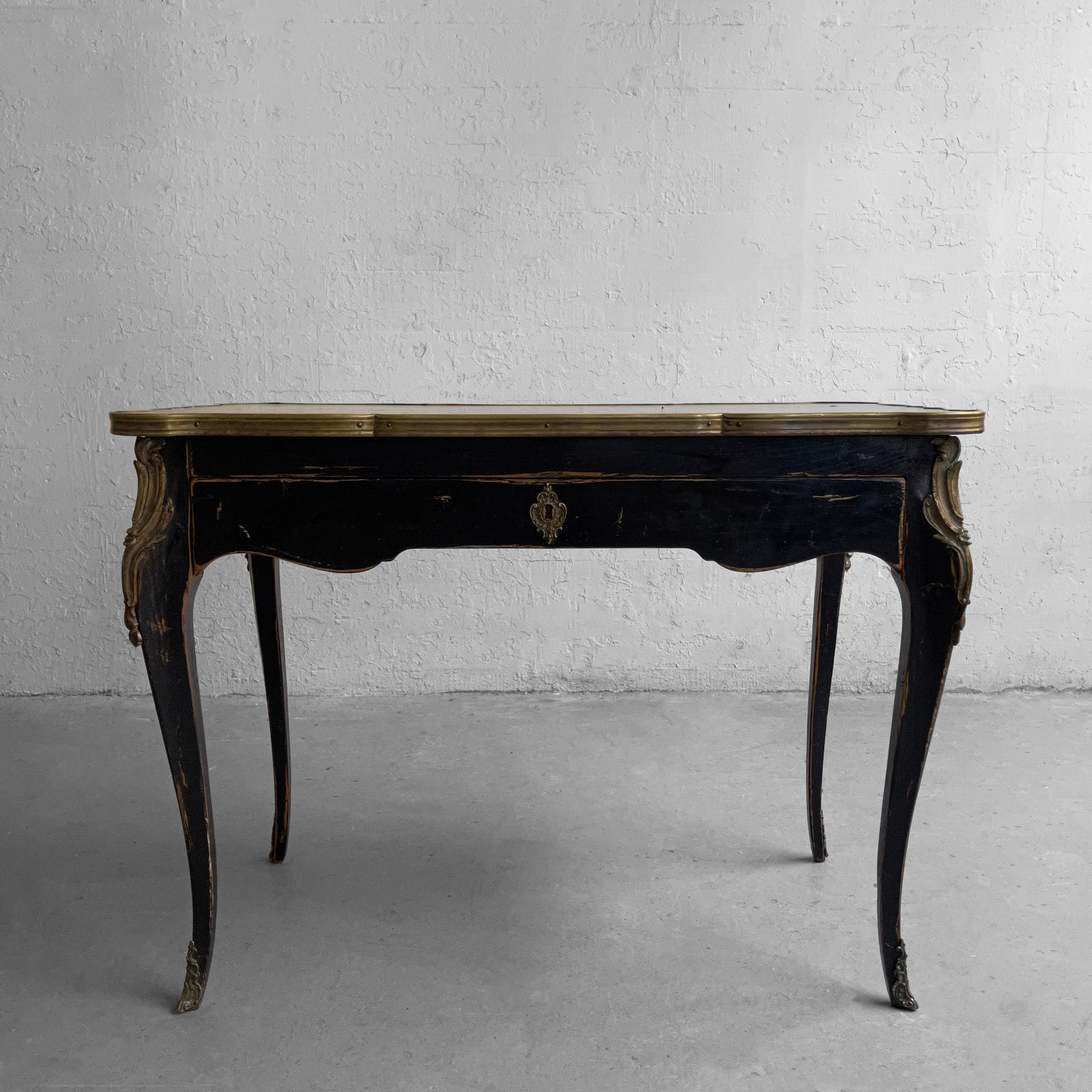 French, Louis XV style, black lacquered chestnut writing desk, circa 1940's features a brass trimmed, embossed leather top with one center drawer and cabriole legs with carved bronze trim detail. The chair clearance is 22.5 inches wide x 23.5 inches