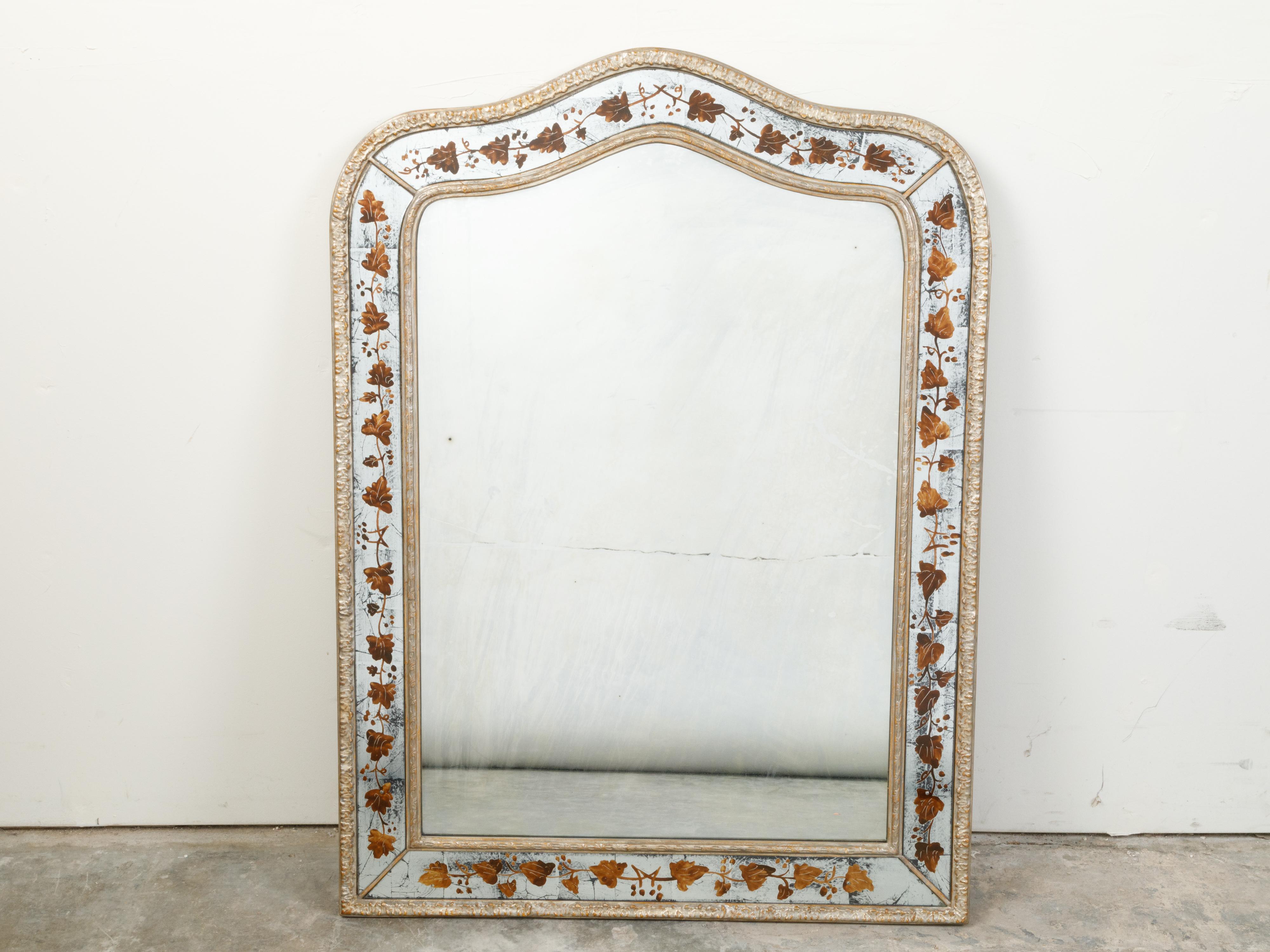 A French Maison Jansen mirror from the mid-20th century, with painted leaves décor. Created by Maison Jansen during the mid-century period, this mirror attracts our attention with its delicate foliage décor accenting a simple frame topped with a