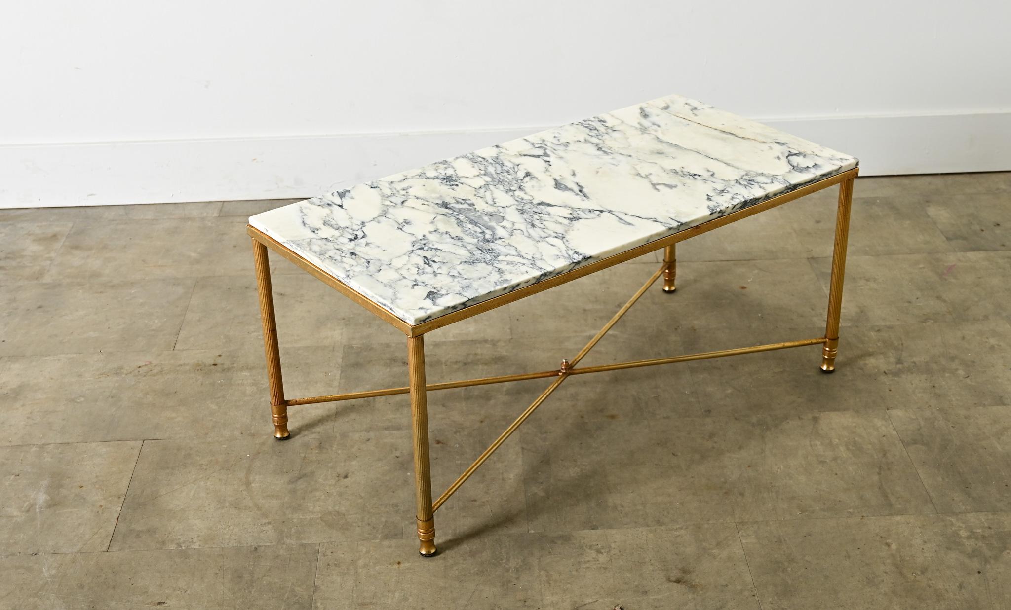 A vintage, midcentury French brass and marble coffee/cocktail table in the style of legendary firm Maison Jansen. Reflecting the typical aesthetic codes of Hollywood Regency taste, the polished brass frame is given a few original twists to modernize
