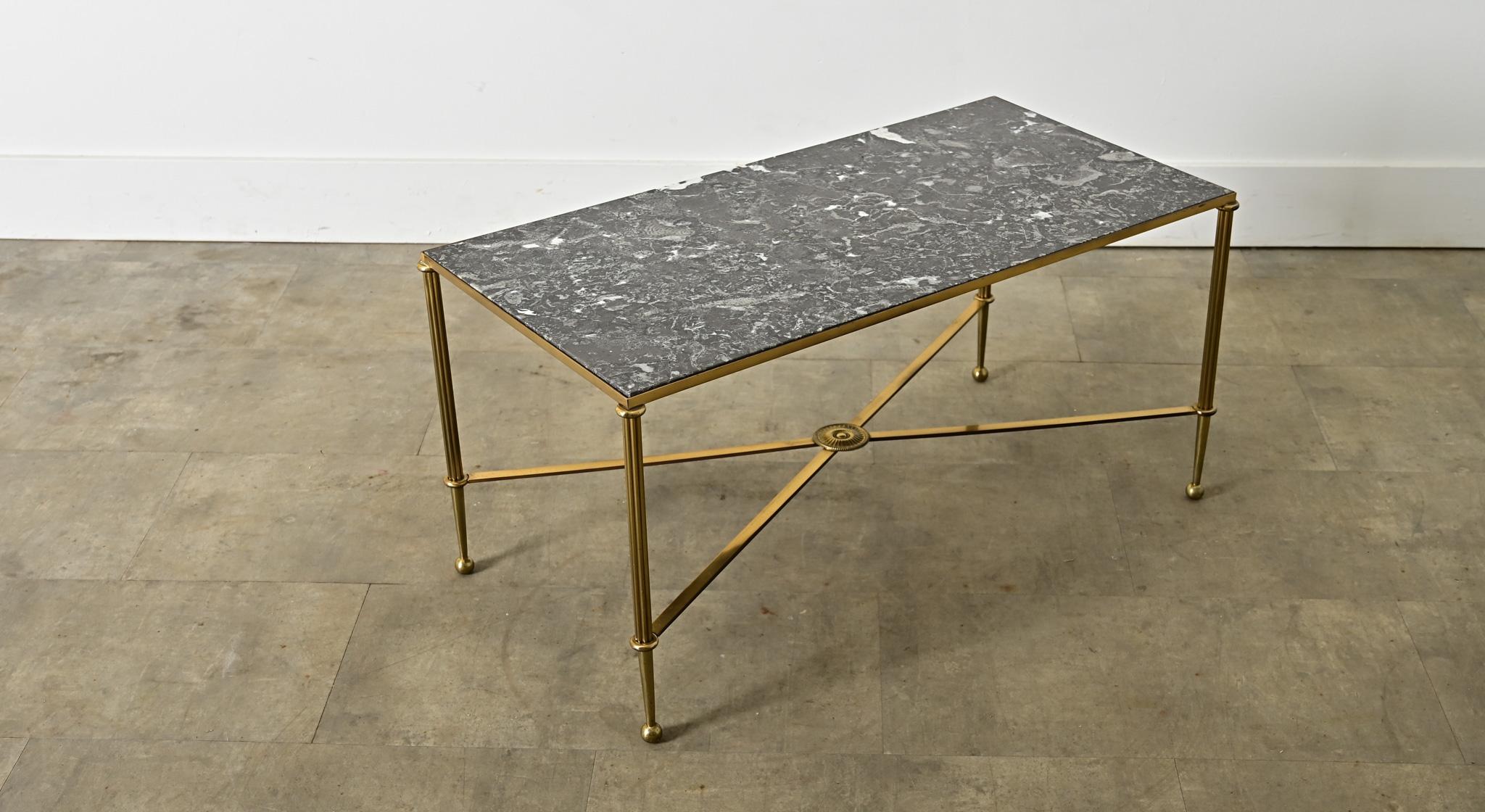 A vintage midcentury French brass and marble coffee/cocktail table in the style of legendary firm Maison Jansen reflecting the typical aesthetic codes of Hollywood Regency taste, given a few original twists to modernize the Neoclassical silhouette.