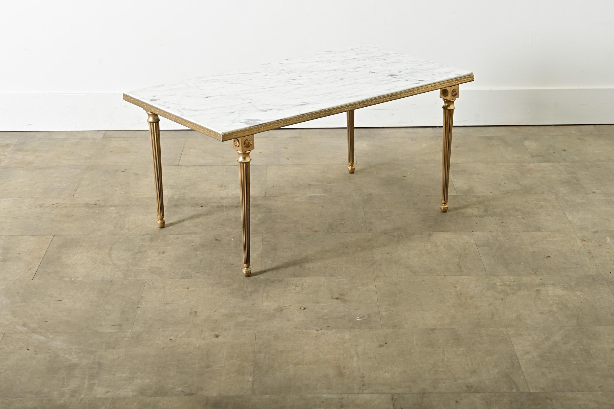 A vintage midcentury French brass and marble coffee/cocktail table in the style of legendary firm Maison Jansen reflecting the typical aesthetic codes of Hollywood Regency taste, given a few original twists to modernize the Neoclassical silhouette.
