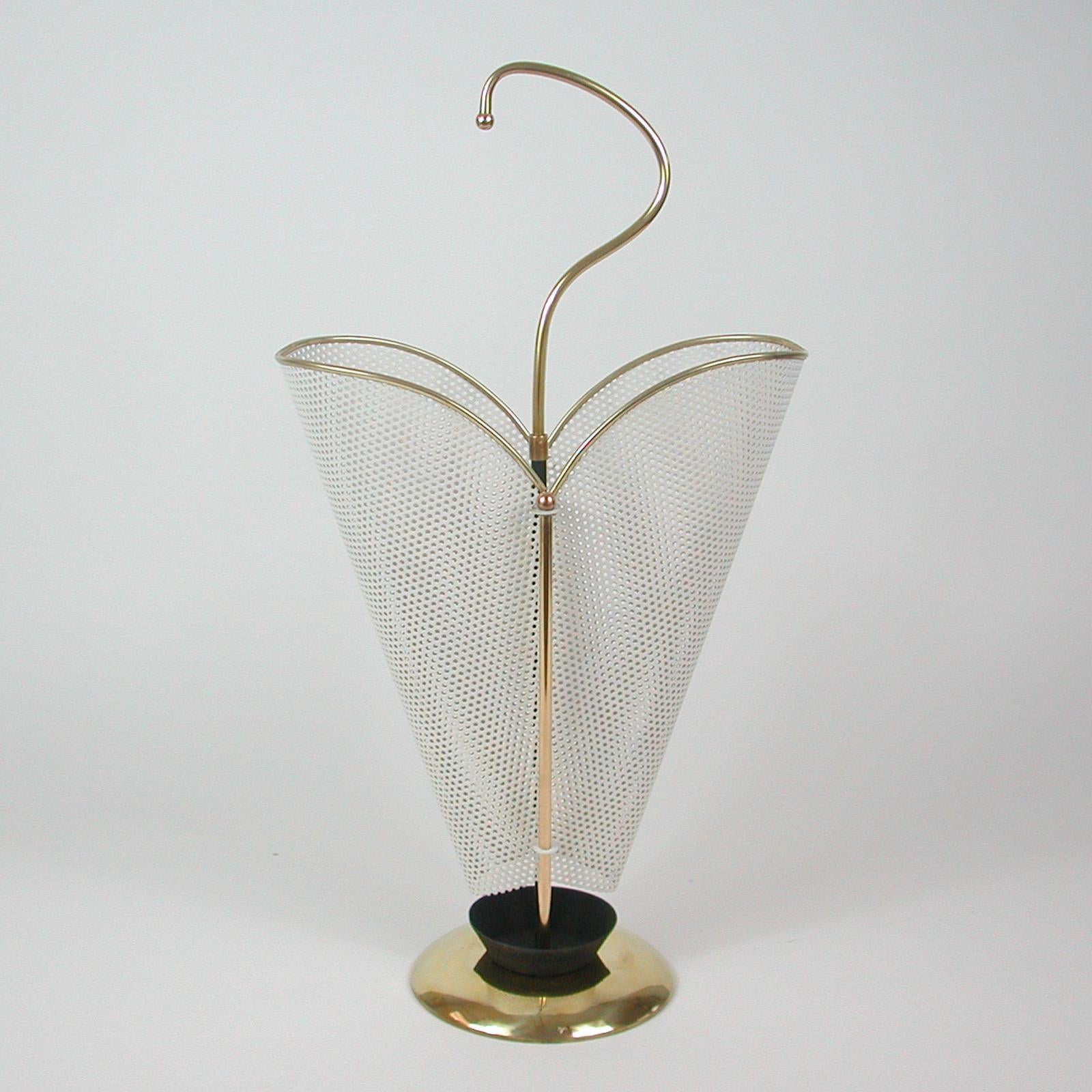 This elegant heart shaped midcentury umbrella stand was designed and manufactured in France in the 1950s in the manner of designer Mathieu Matégot. It features off white lacquered iron mesh or perforated metal, a brass base and a stylish brass