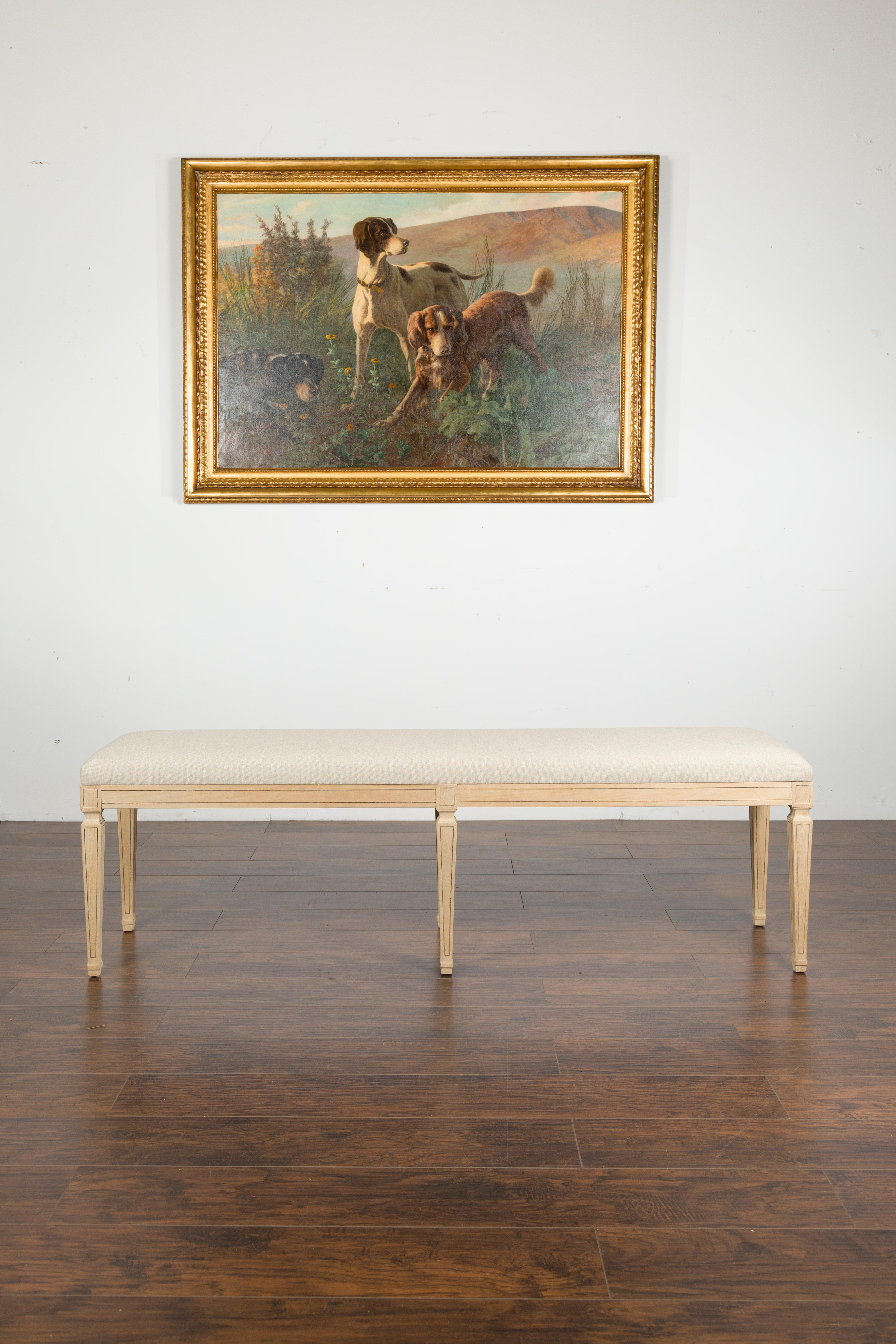 A French vintage Neoclassical style bleached wood bench from the 20th century, with new upholstery and tapered legs. Created in France during the midcentury period, this Neoclassical style bench features a long rectangular seat, newly recovered with