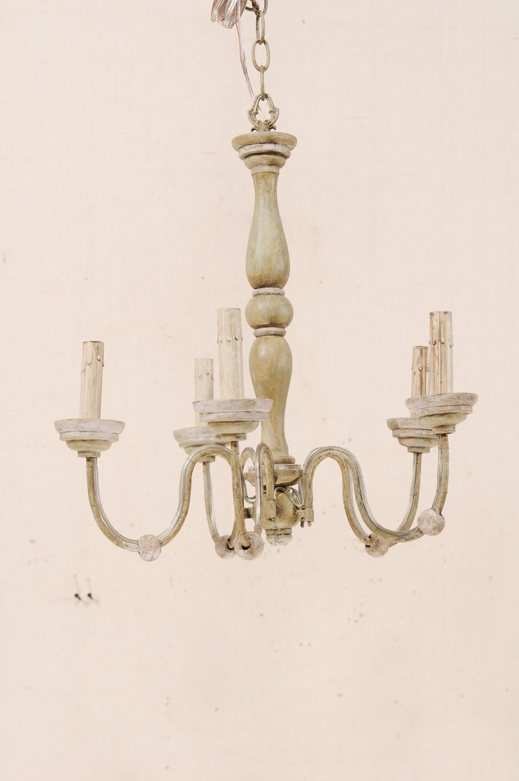 A French midcentury five-light painted wood and metal chandelier. This mid-20th century chandelier from France features a turned wood column with fluid s-shaped swooping arms lifting up and out from the bottom. The five metal arms are each adorn