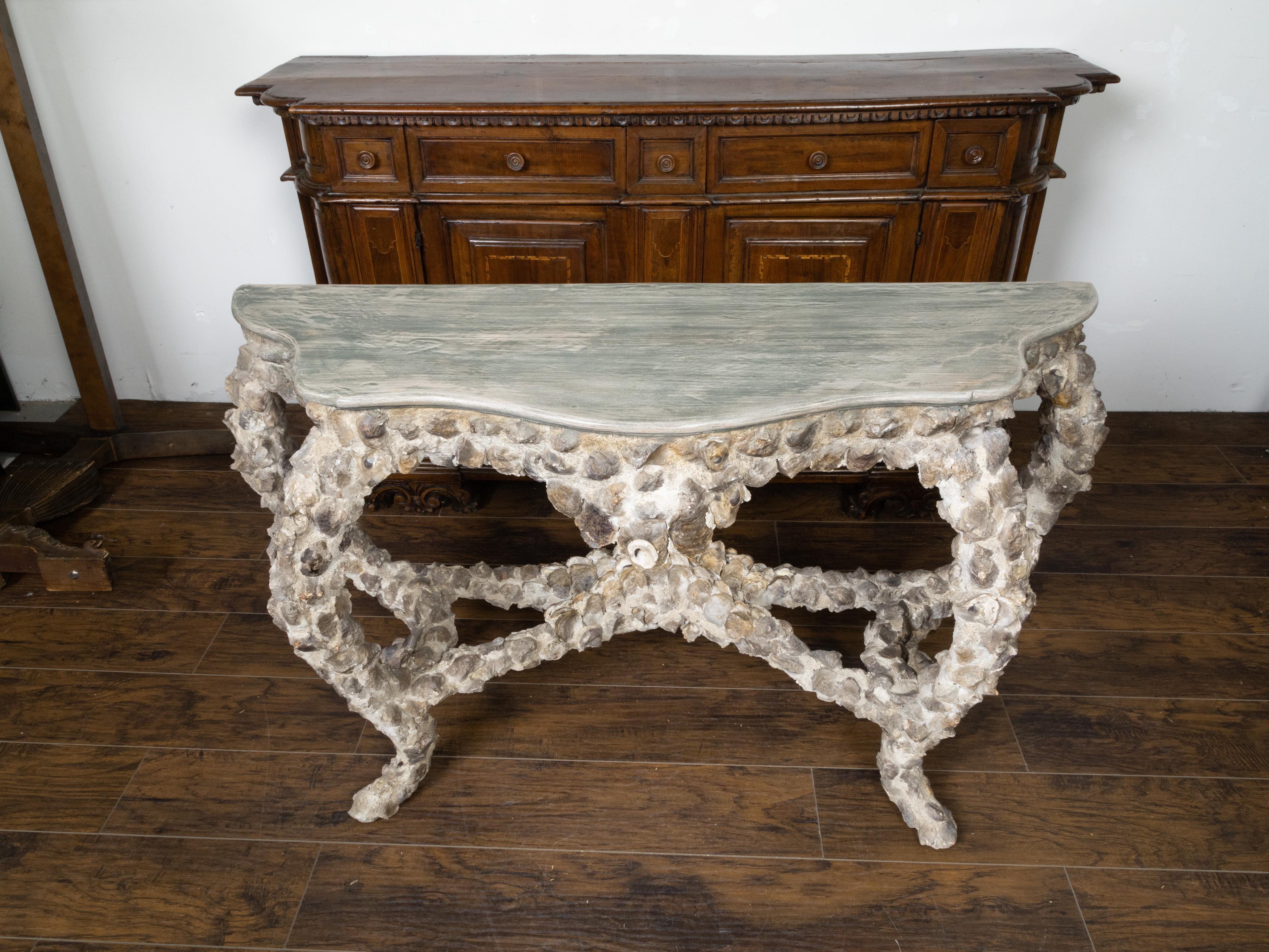 A French vintage oyster shell grotto console table from the mid 20th century, with painted wood top. Created in France during the midcentury period, this console table captures our attention with its oyster shell grotto base supporting a painted