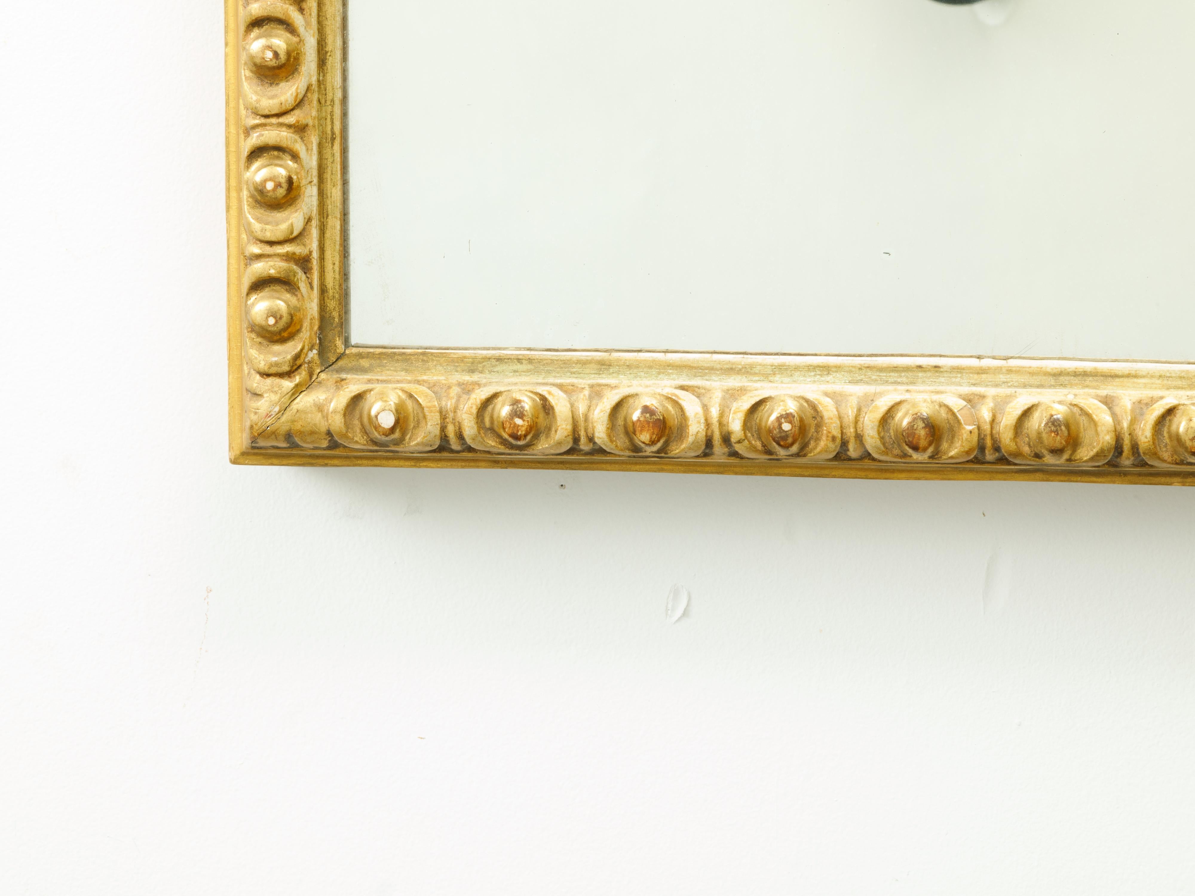 A French giltwood rectangular mirror from the mid-20th century, with carved ovoid motifs. Created in France during the midcentury period, this rectangular mirror features a carved giltwood frame adorned with a regular rhythm of ovoid motifs