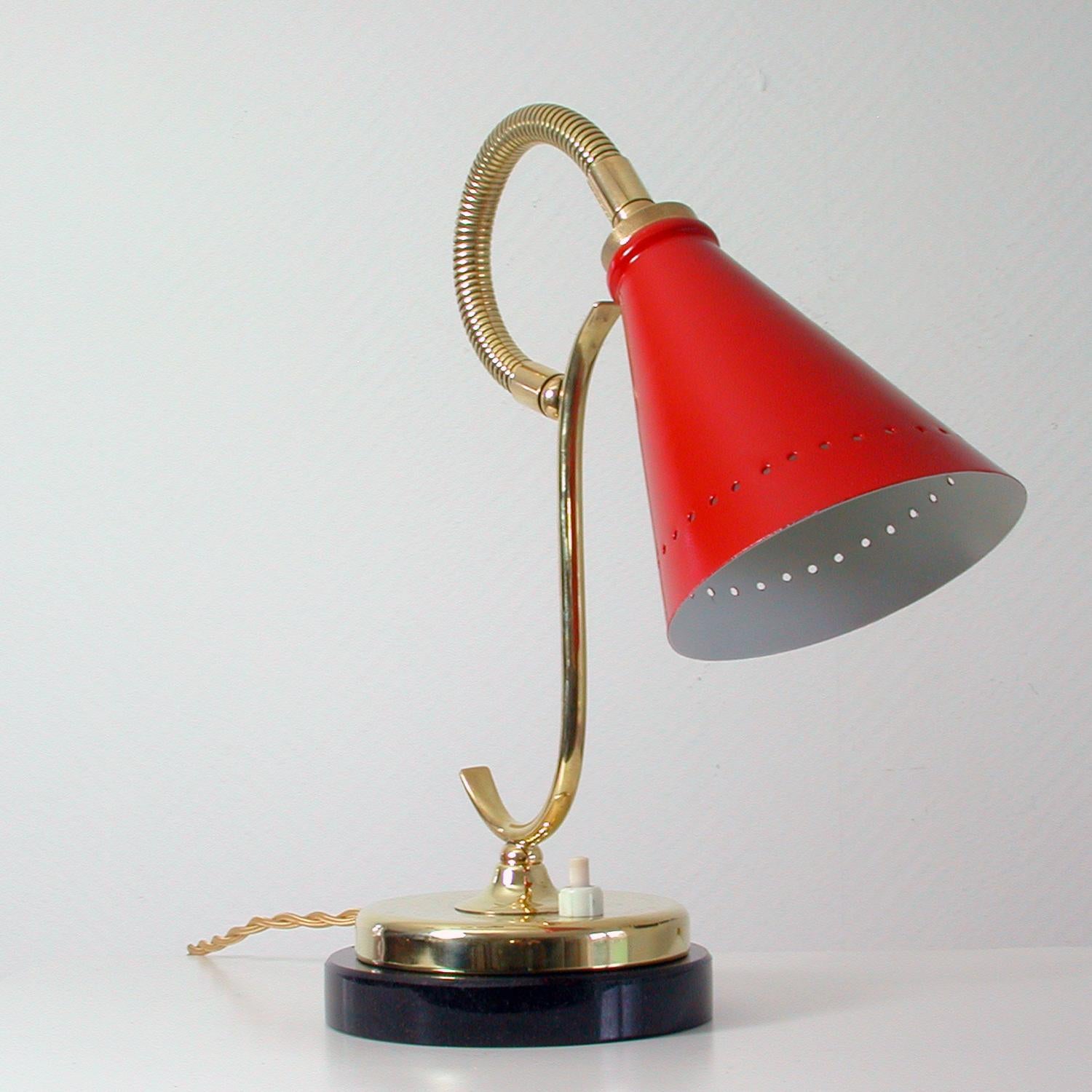 This midcentury table lamp was designed and manufactured in France in the 1950s.
It has got a red lacquered aluminum lamp shade, an adjustable brass gooseneck lamp arm, brass lamp foot and stands on a black marble base.
The lamp has got a French
