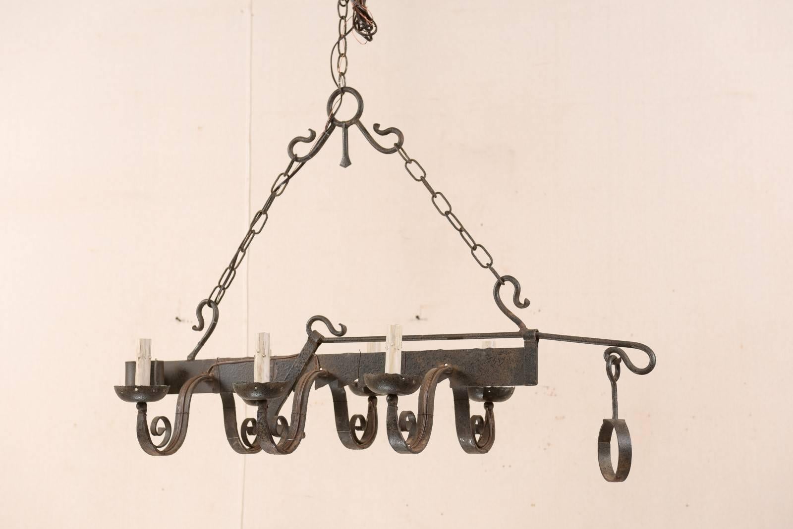 A French midcentury, six-light, forged-iron chandelier fashioned from a 19th century spit-jack. A spit-jack is a type of rotisserie that was once common in fireplaces. This chandelier has six swooping arms with scrolled centers, which connect to the