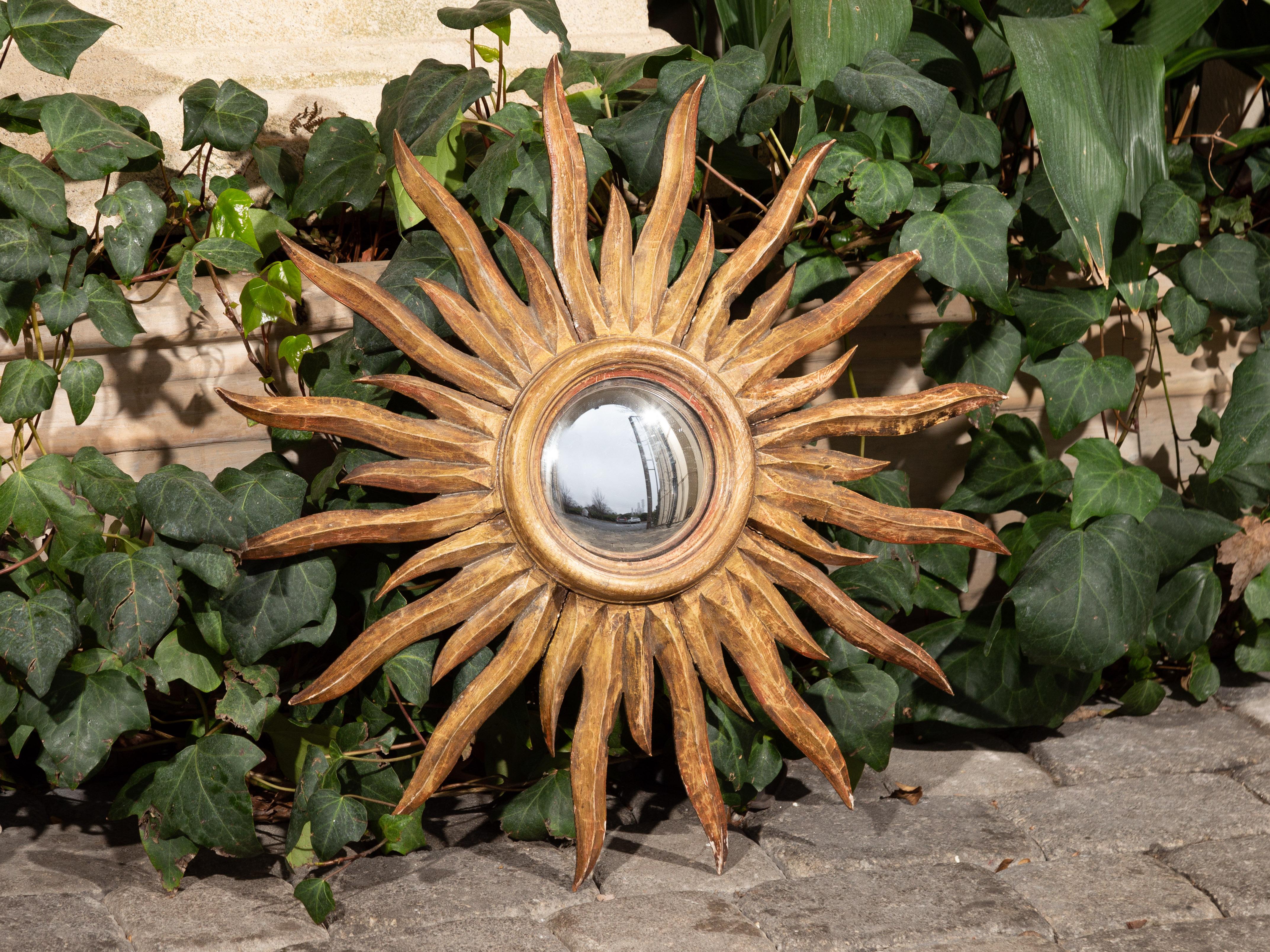 A French painted sunburst mirror from the mid-20th century, with wavy sun rays. Created in France during the mid-century period, this sunburst mirror features a convex mirror plate, surrounded by elegant sun rays of two different sizes, brightening