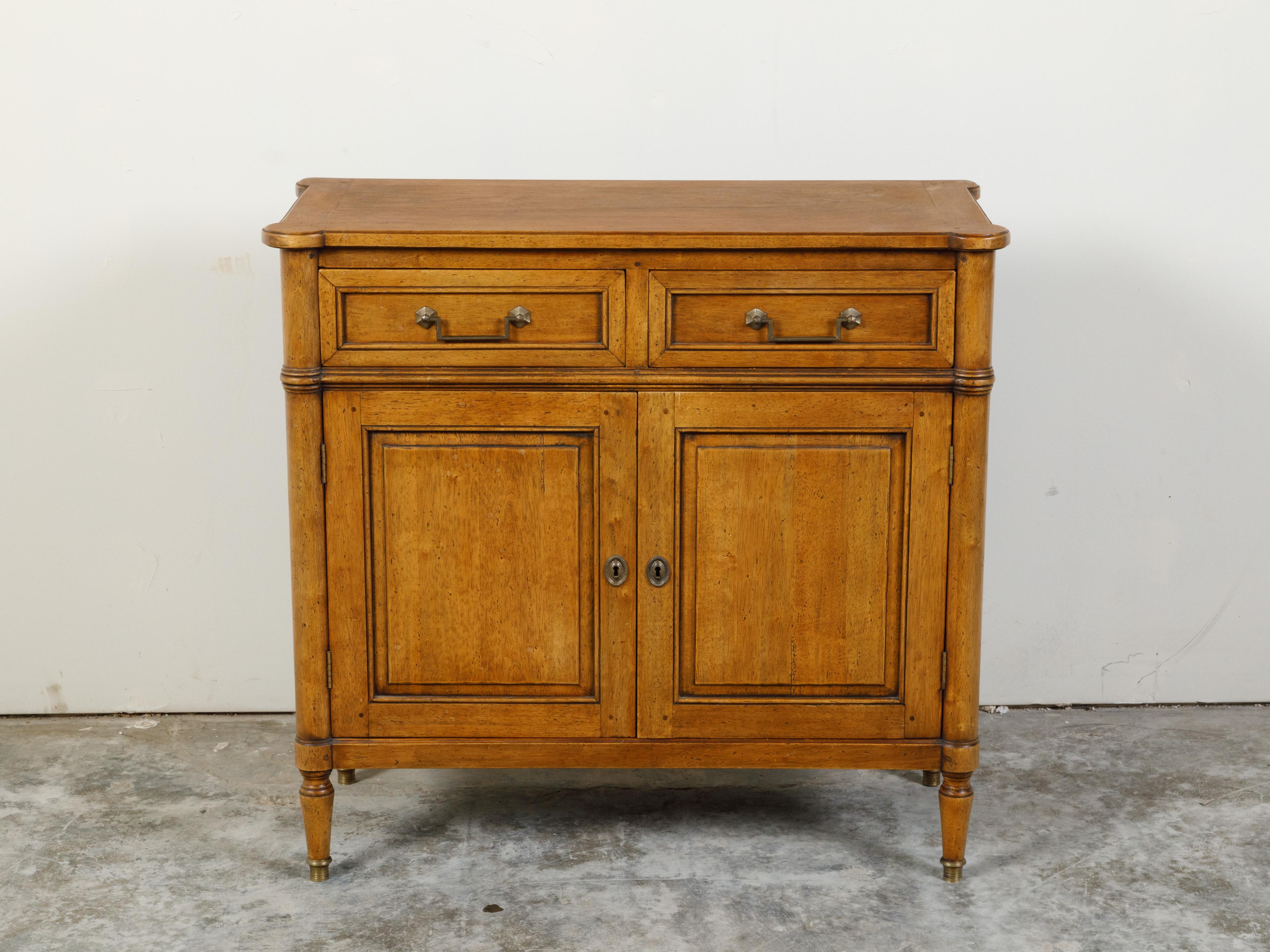 A French walnut buffet from the mid 20th century, with two drawers over two doors and brass hardware. Created in France during the midcentury period, this walnut buffet features a rectangular top with rounded corners, sitting above two drawers with