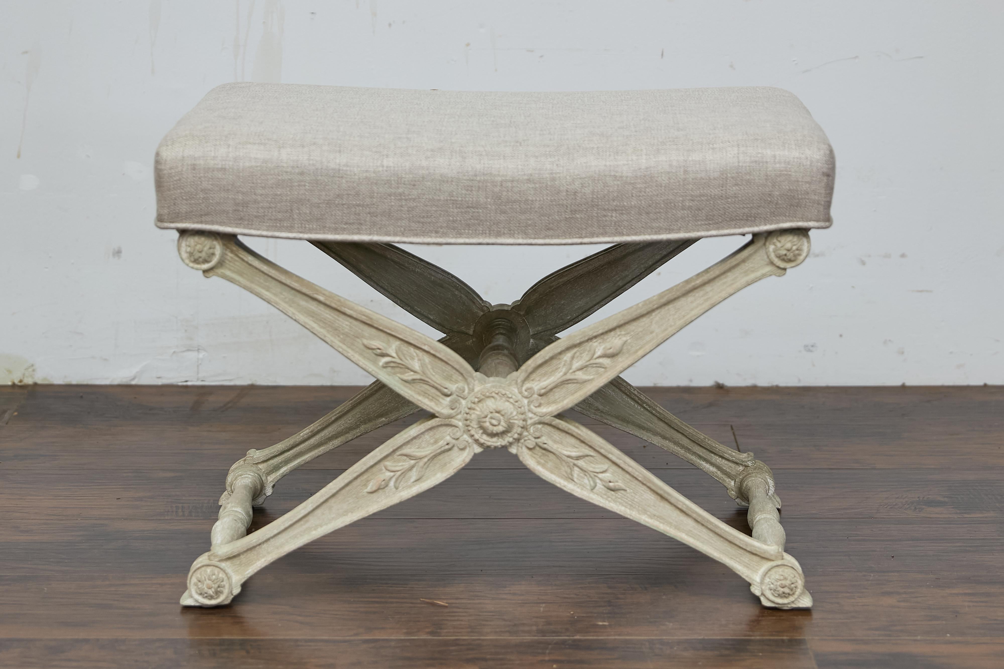 Taburete francés de mediados de siglo con base en forma de X tallada con follaje y tapicería a medida. Este exquisito taburete curule francés de mediados de siglo cautiva con su elegante acabado encalado y su intemporal base en forma de X. El